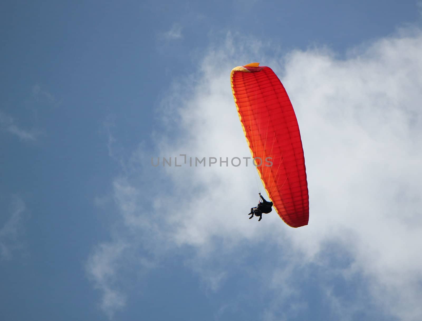 Man flying in the cloudy sky with its red paragliding