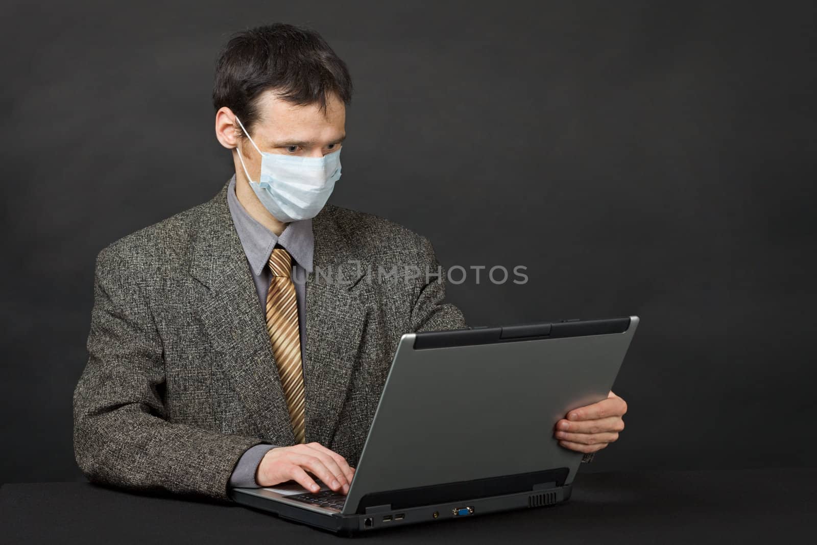 Person with medical mask working in Internet by pzaxe