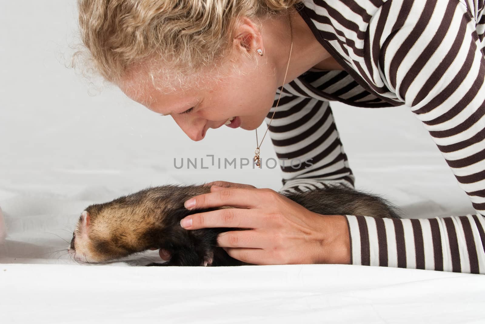 Woman playing with polecat in studio on white background