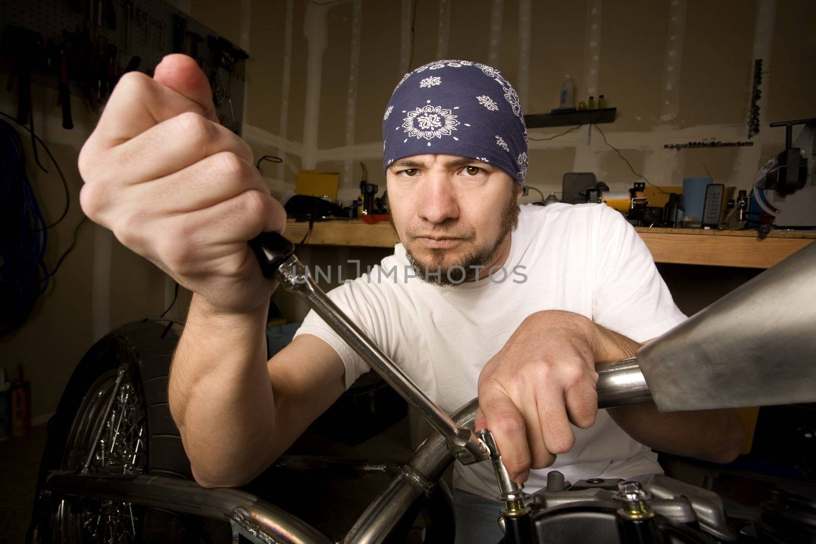 Hispanic mechanic working on a chopper style motorcycle