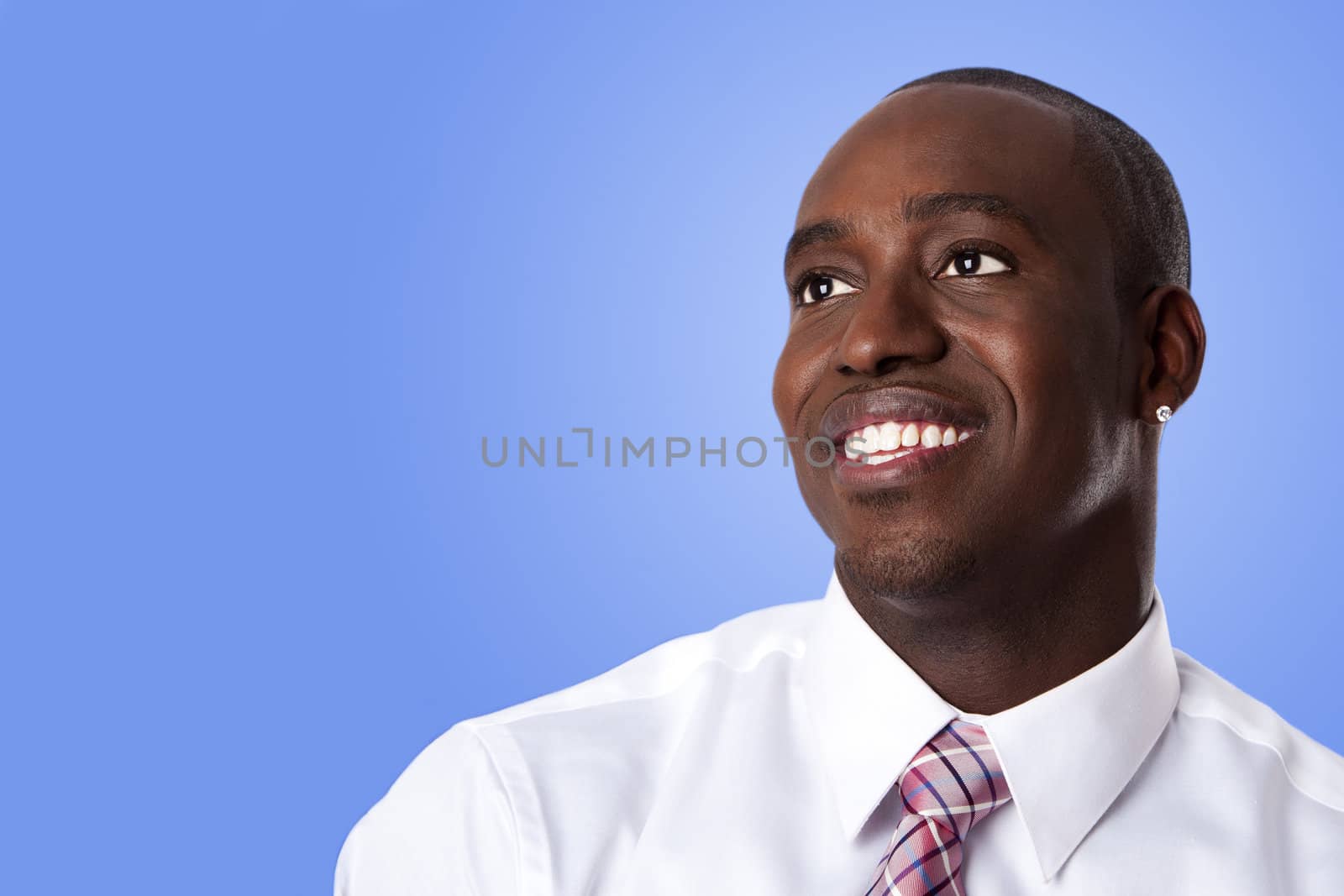 Face of handsome happy African American corporate business man smiling, wearing white shirt and pink with stripes necktie on a blue sky-like background.