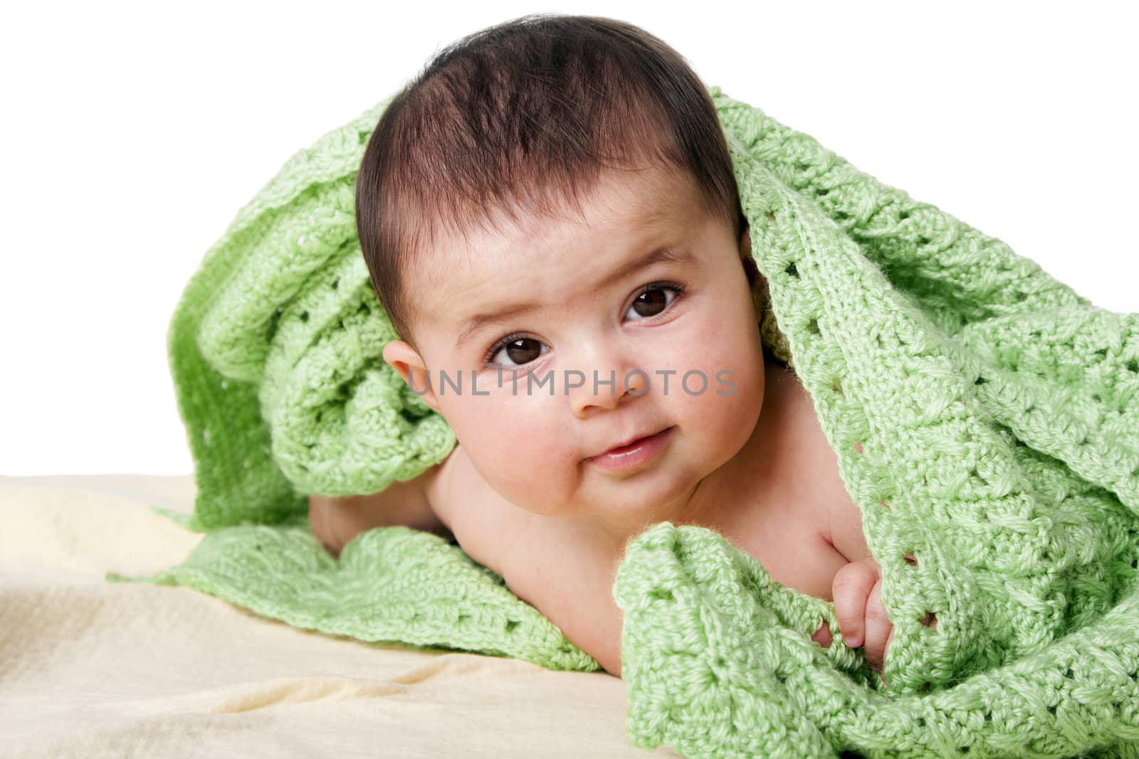 Beautiful cute happy Caucasian Hispanic baby face while laying and covered between green knitted blankets, isolated.