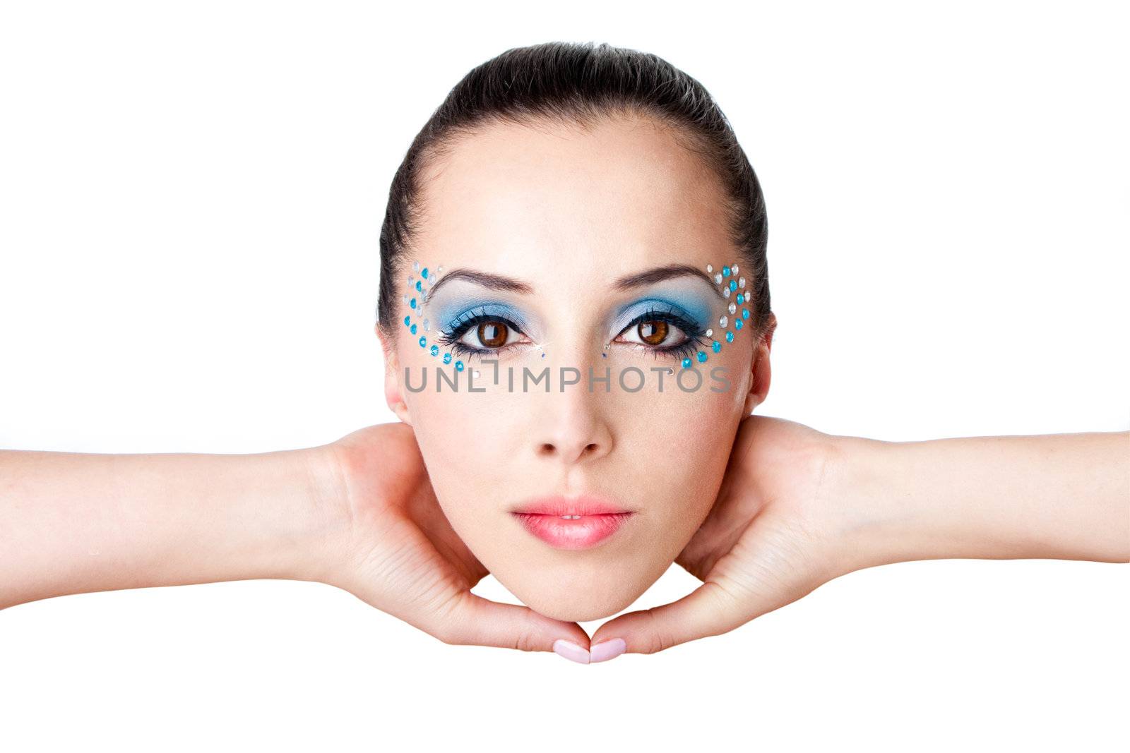 Beautiful female fashion face with blue makeup and gems rhinestones of a Caucasian Hispanic woman held with hands in the air, isolated.