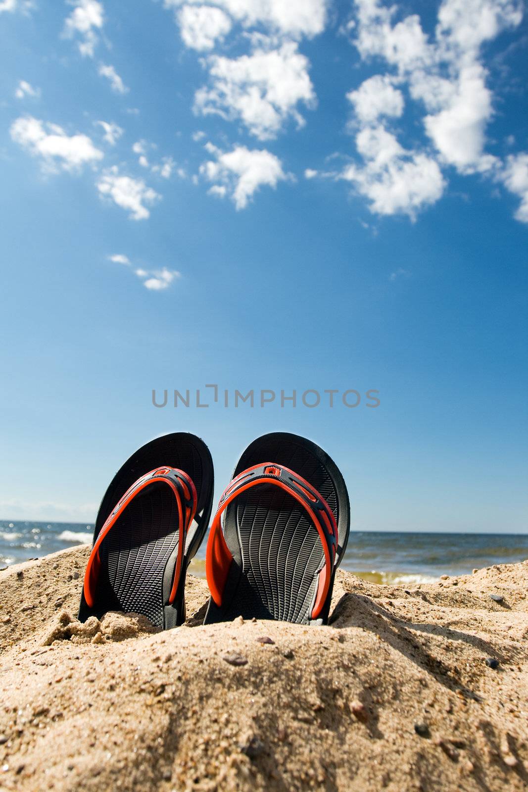 Pair of plastic beach slippers at the seashore