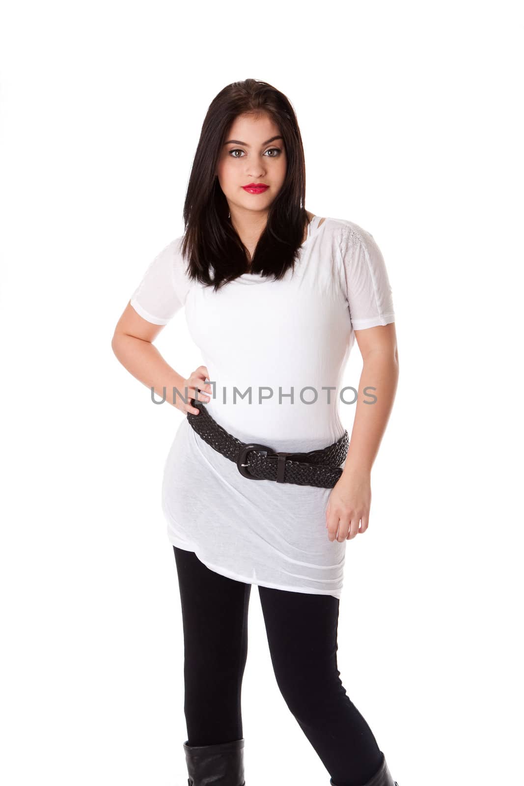 Beautiful brunette Caucasian Hispanic Latina woman with red lipstick standing with hand on hip, wearing white shirt and black leggings, isolated.