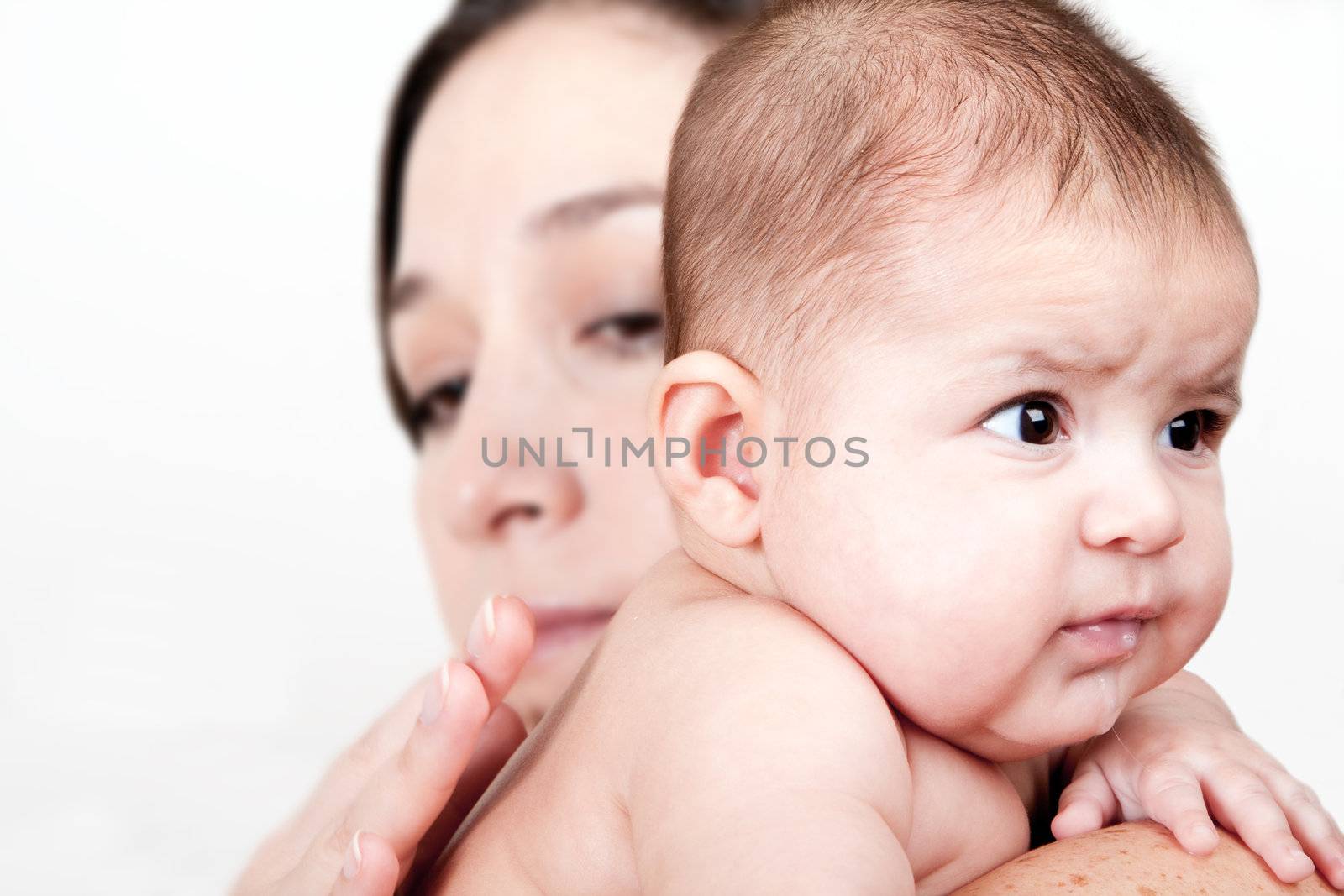 Beautiful Caucasian Hispanic Latina mother holding drooling baby over shoulder and tapping on back so infant can burp, isolated.