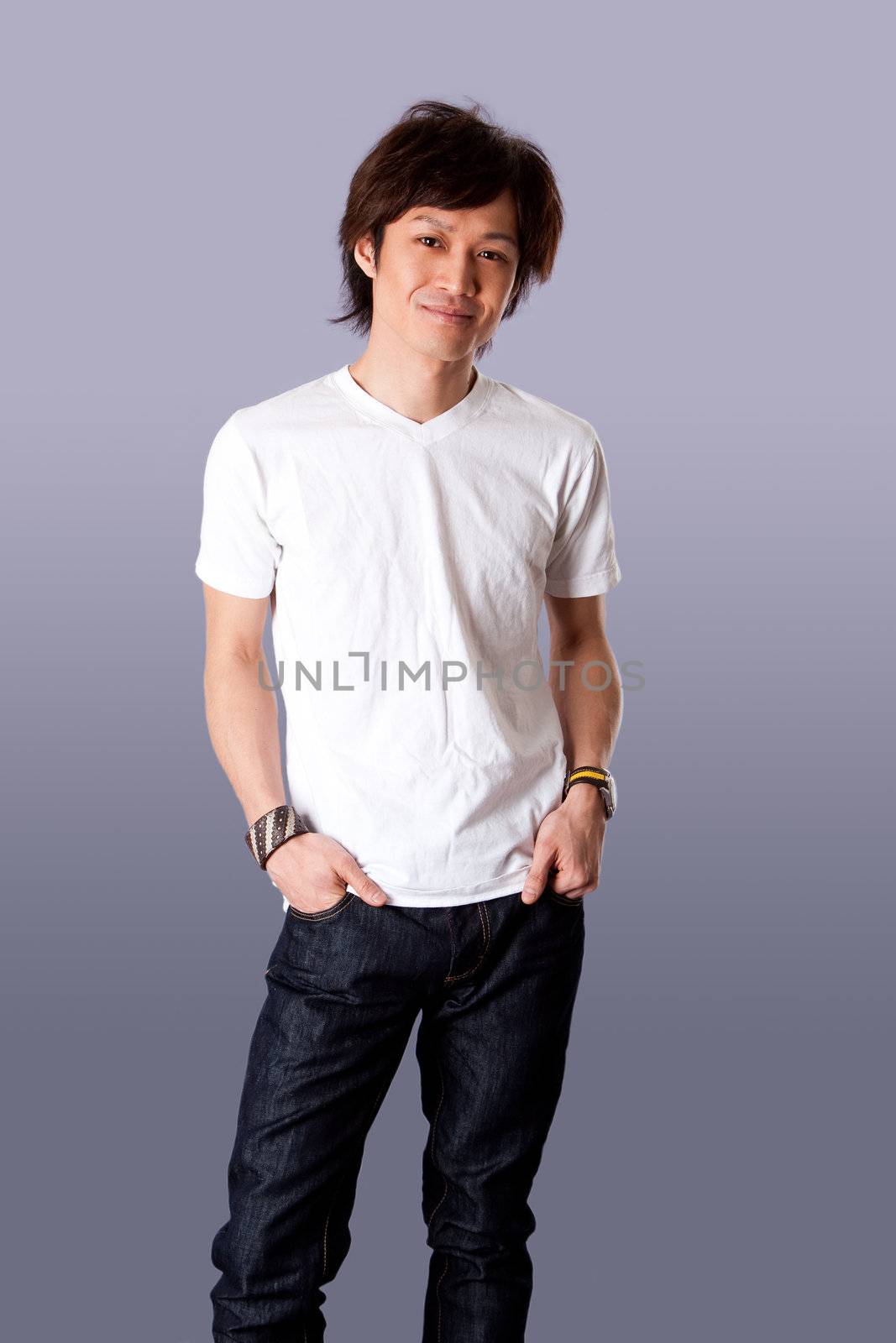 Smiling casual Asian man wearing white shirt and jeans standing with hands in pockets and happy expression, isolated.