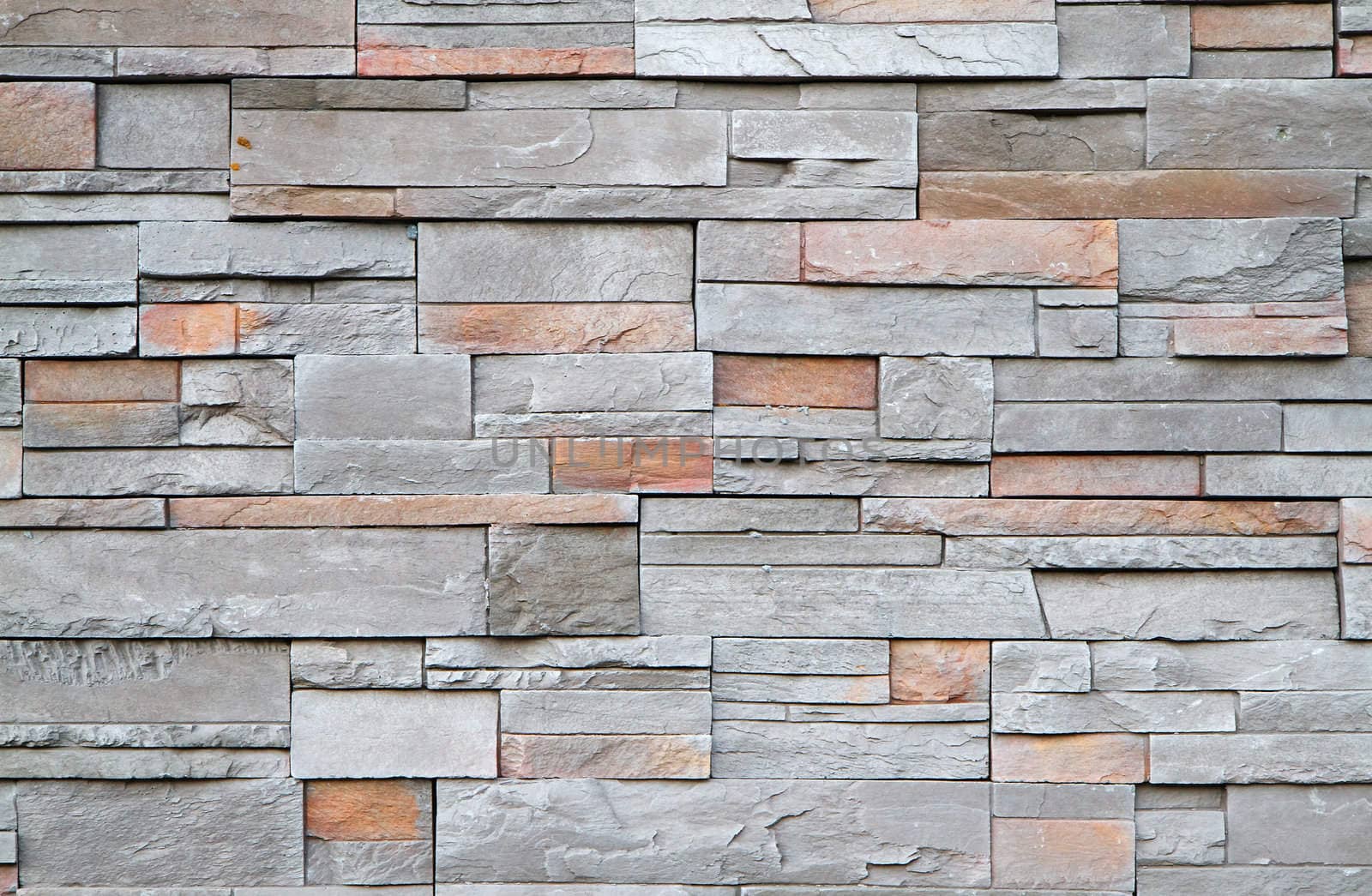 Gray, brown, red flat stone wall in a random pattern