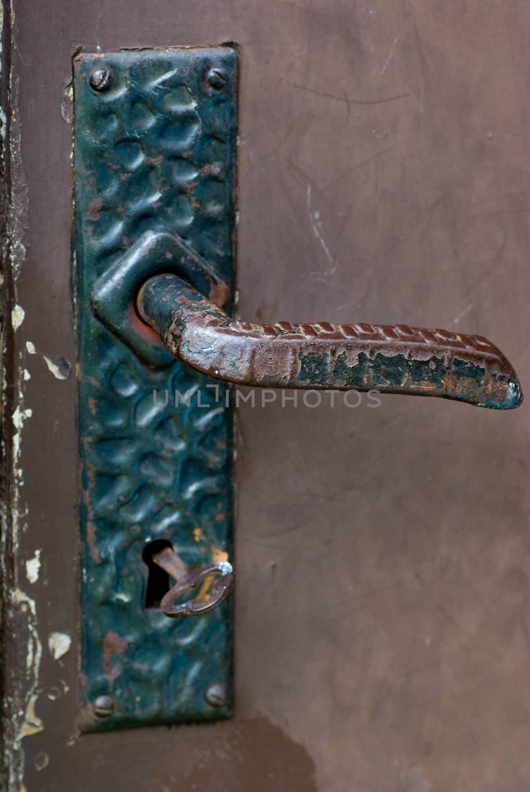 And old iron door handle with a key in the lock