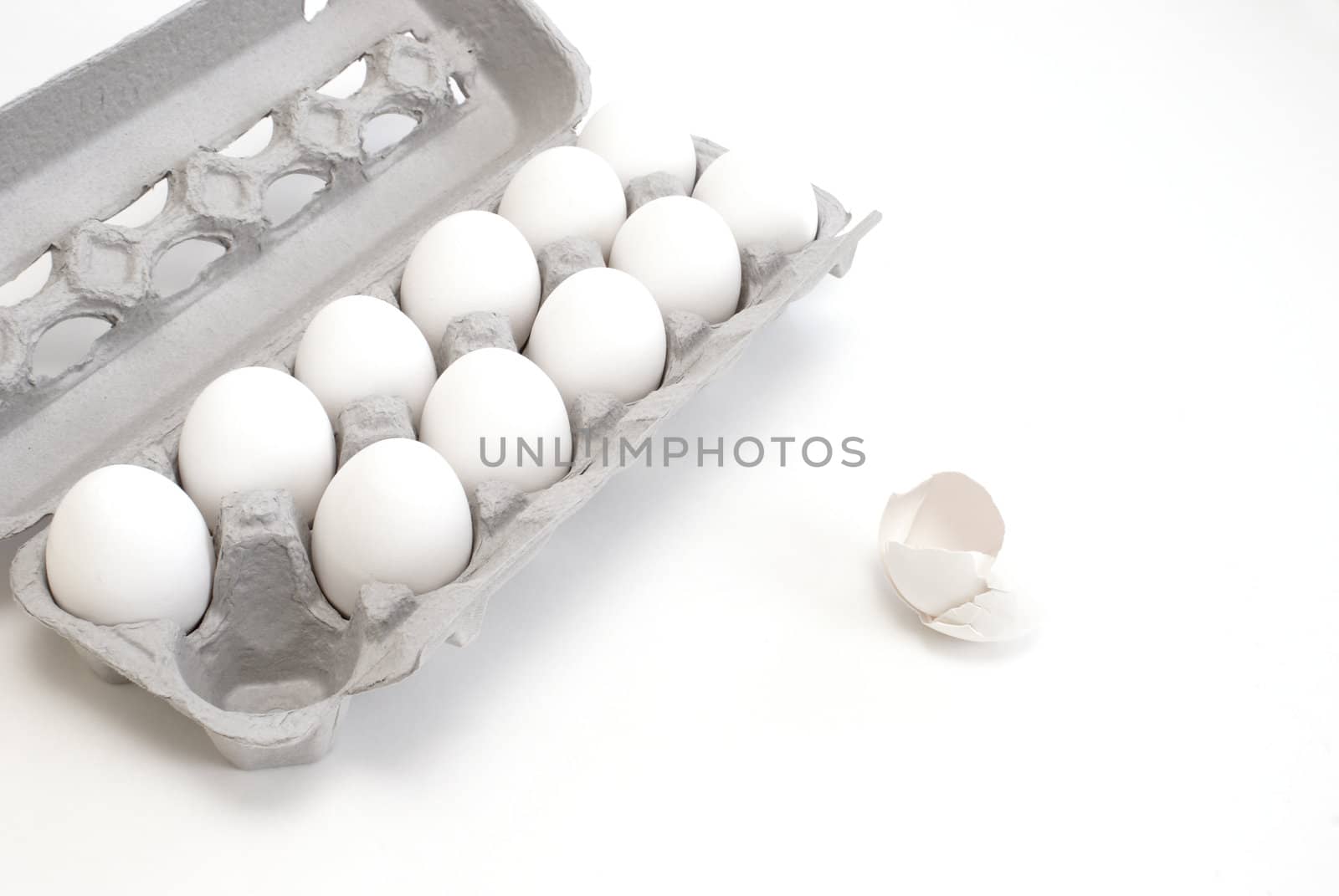 A carton of white eggs with one egg used.