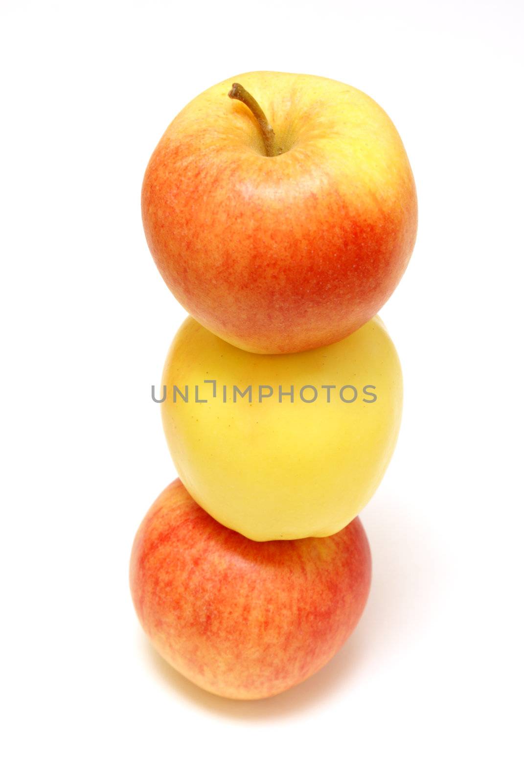 A yellow apple is stuck in the middle of two red ones.