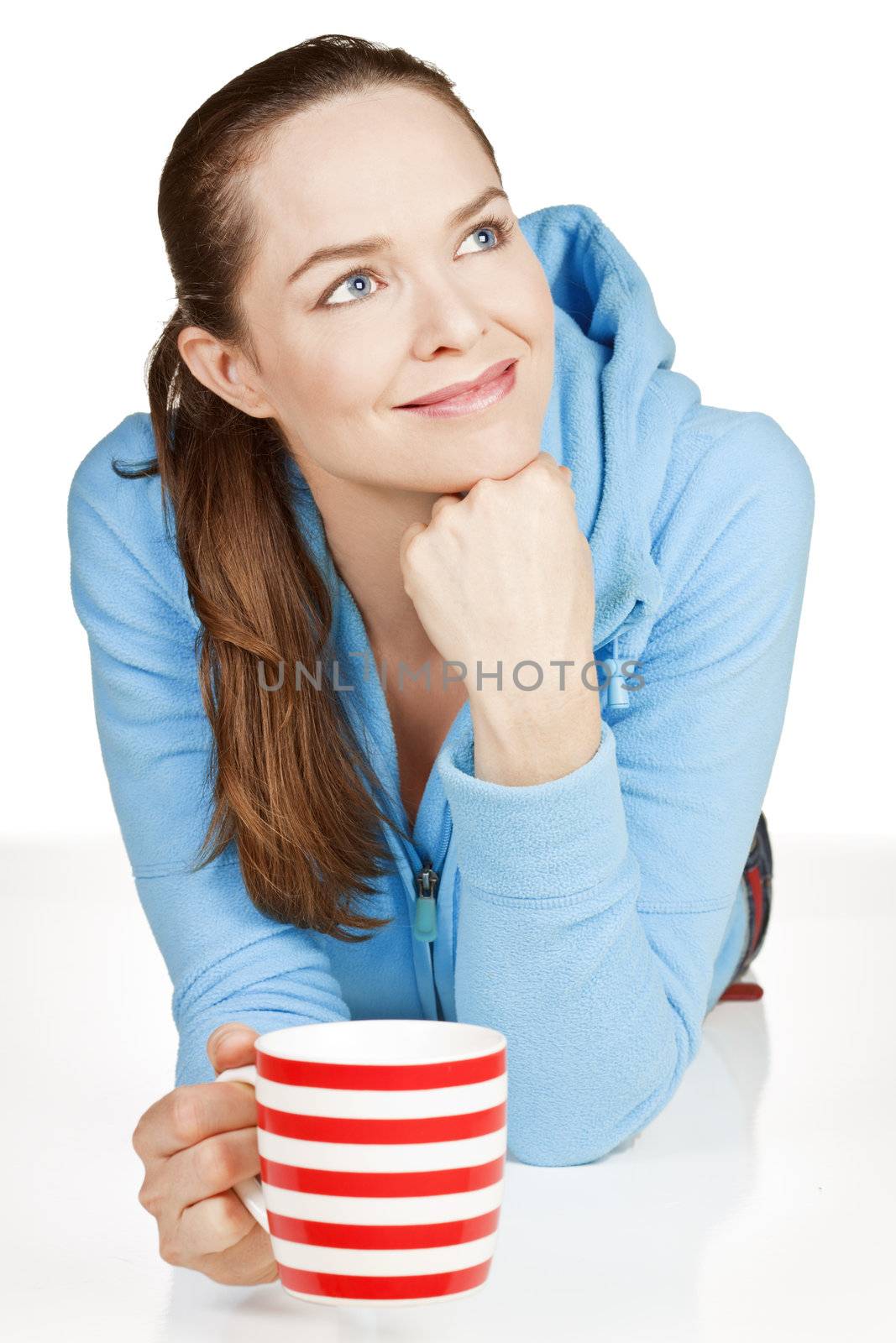 A beautiful young healthy woman lying down with a cup of tea or coffee smiling. 