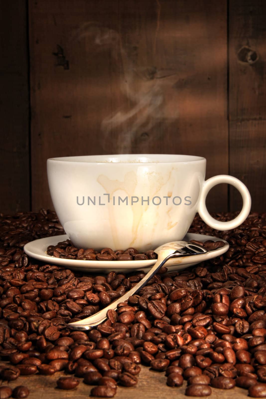White coffee cup with spoon on roasted beans  by Sandralise