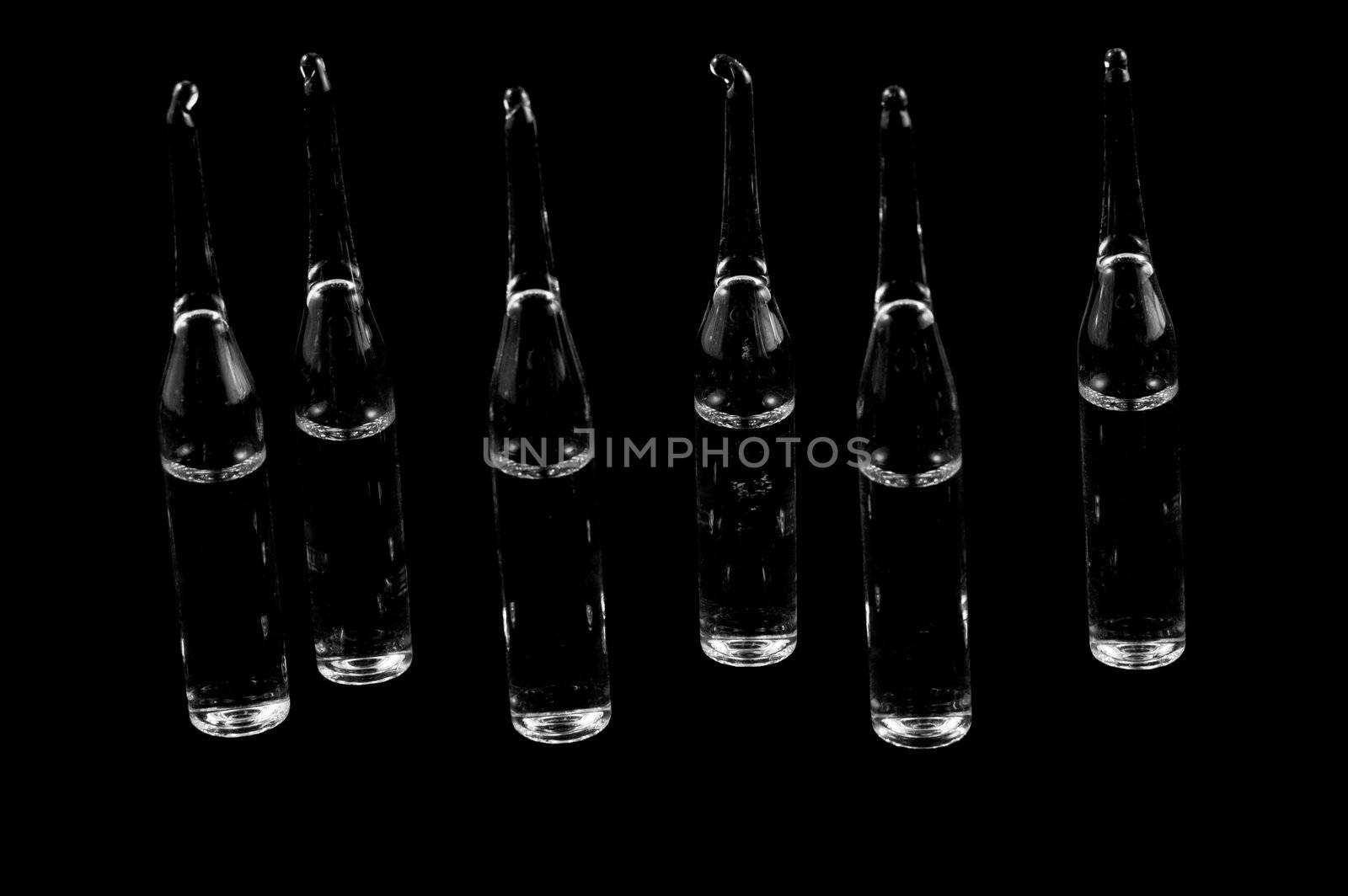 six medical transparent ampoules on a black backgroun