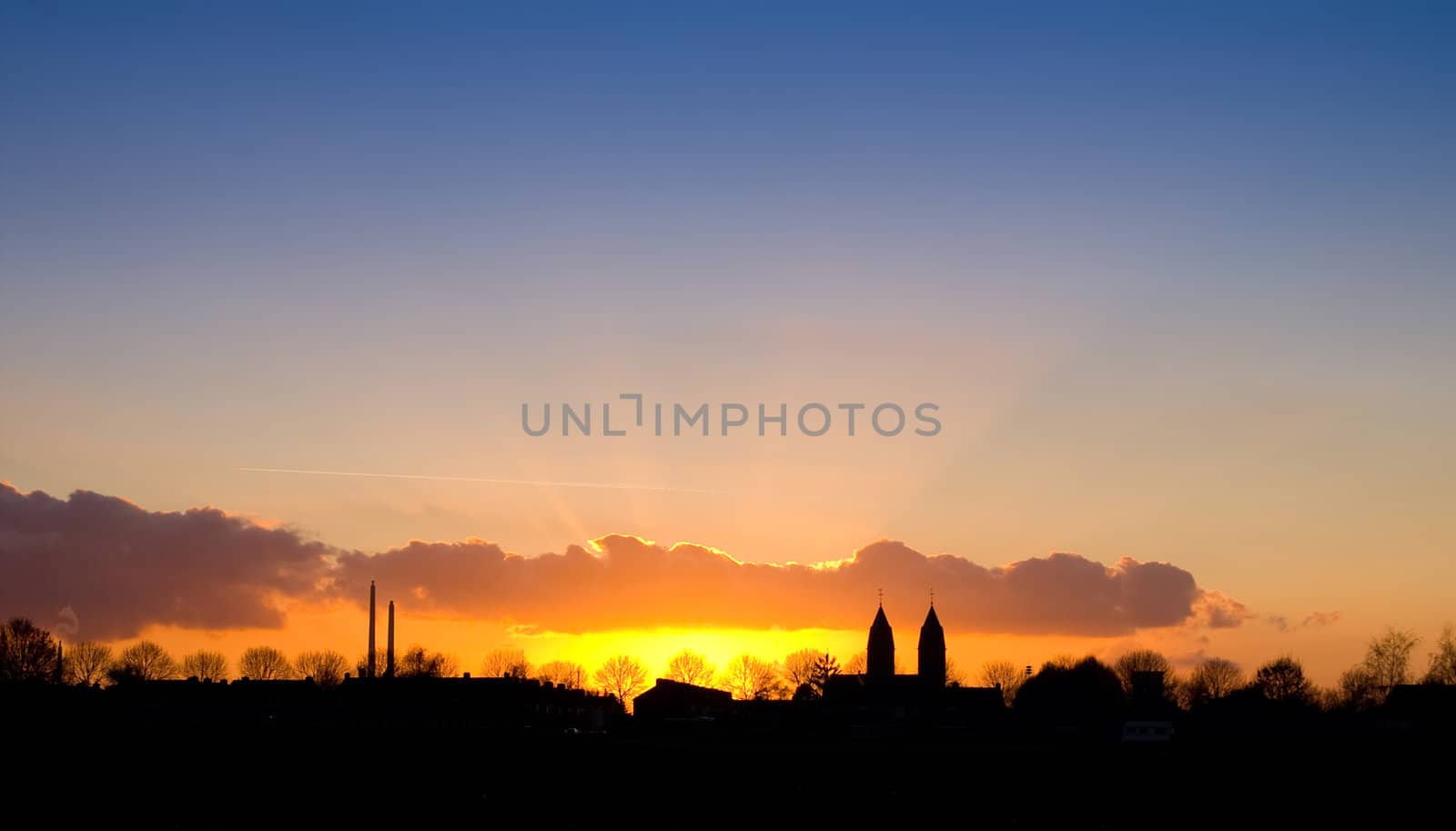 nice sunset with a silhouette of a village with church towers 
