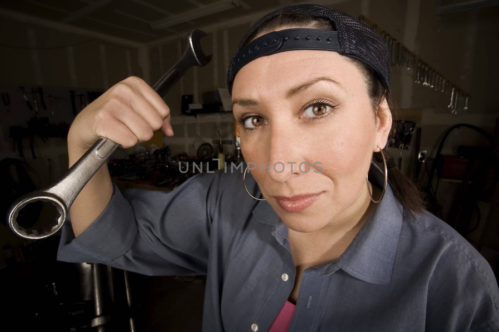 Hispanic woman in a garage with wrench