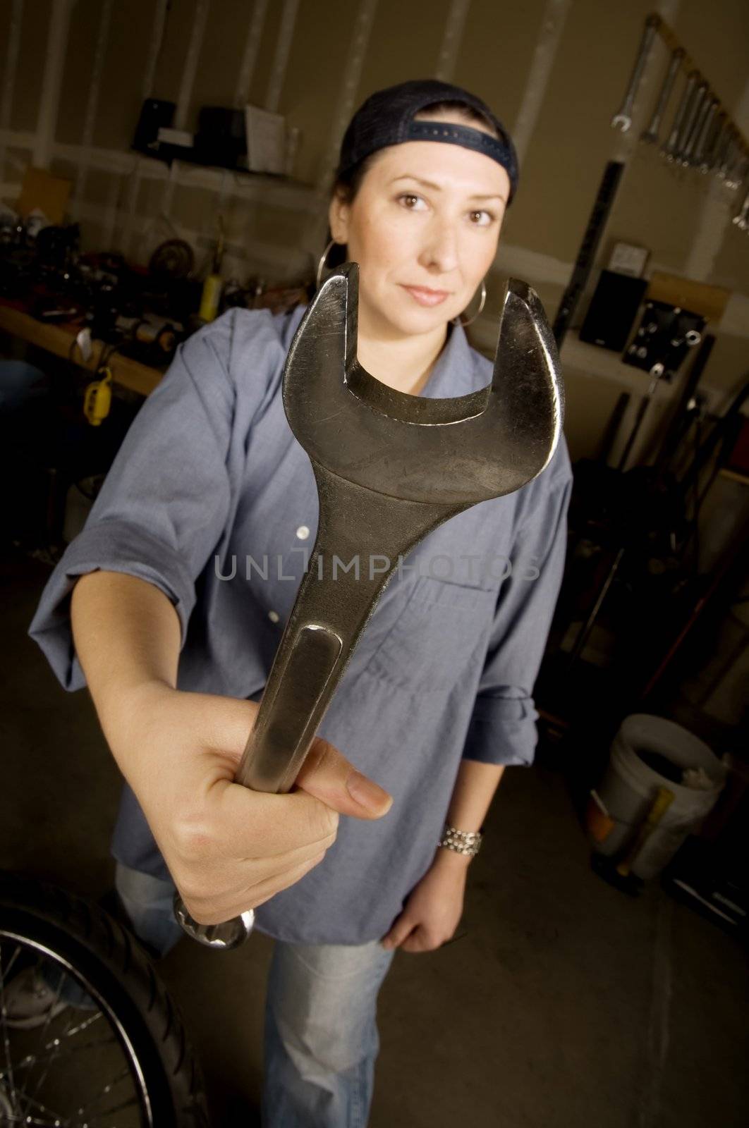 Hispanic woman in a garage with wrench