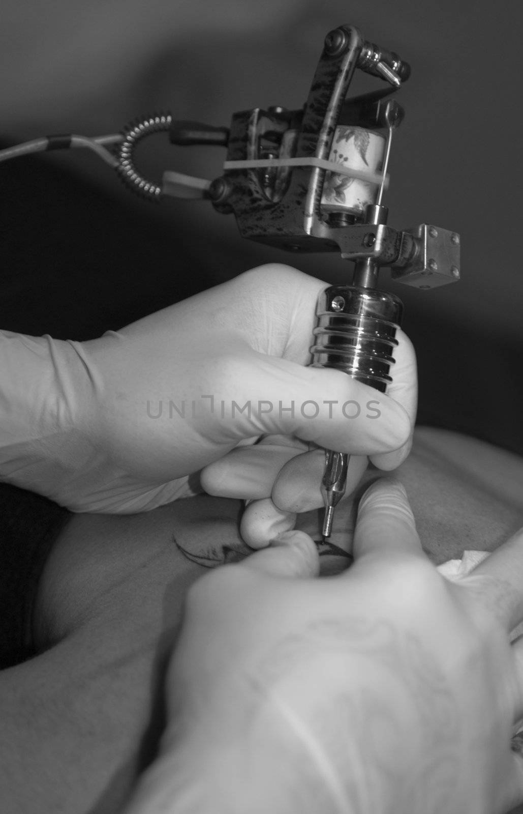 an young artist man tattooing a woman with a professionnal stylet