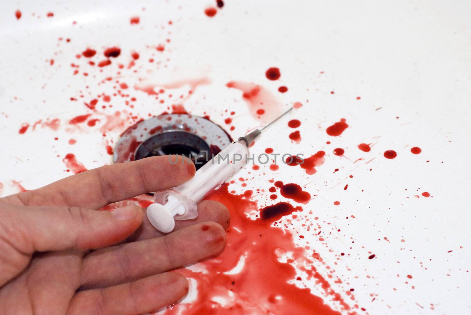 human hand with a serynge  and  blood in a bathroom: suicide in a tub