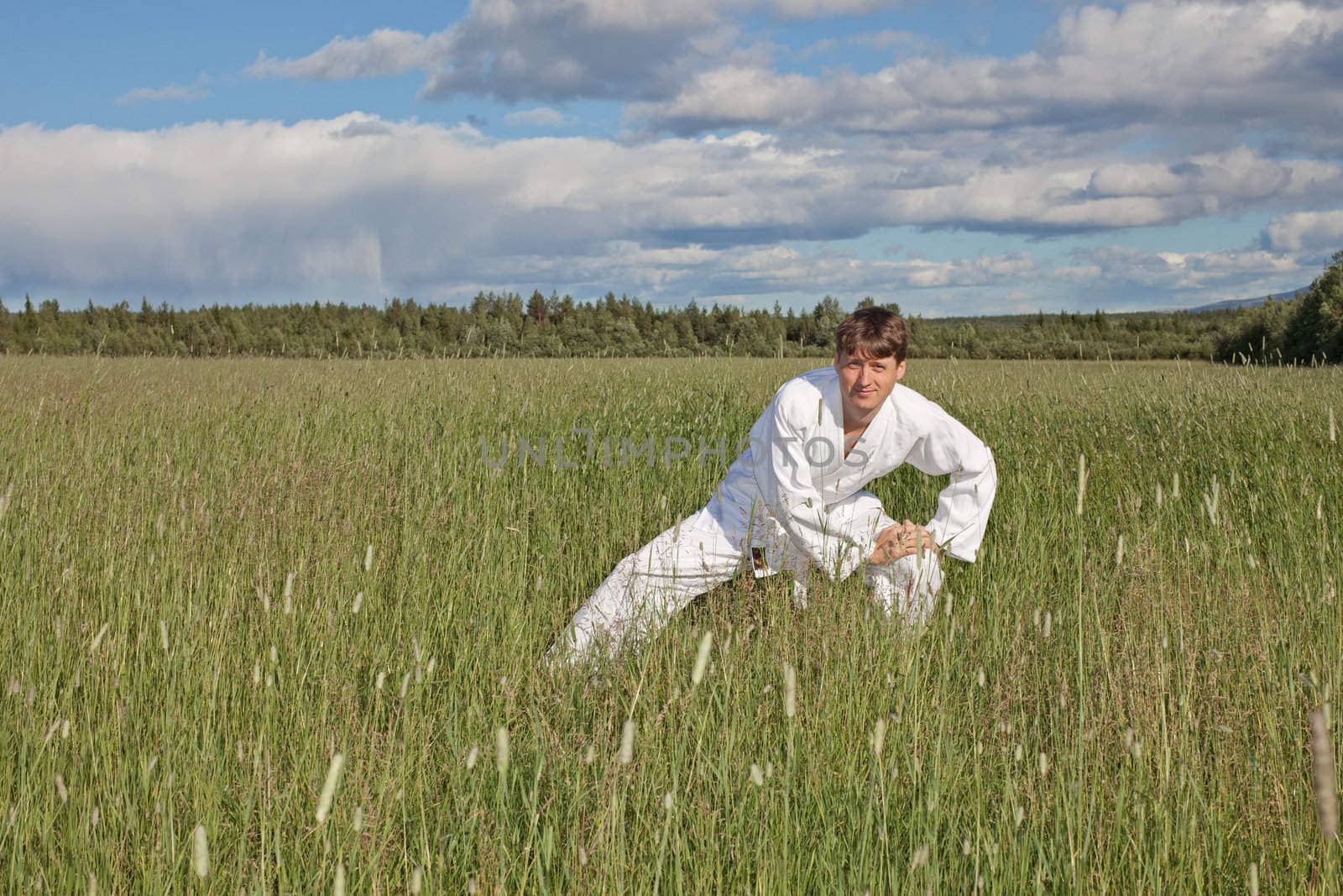 The young man practices Wushu in the field