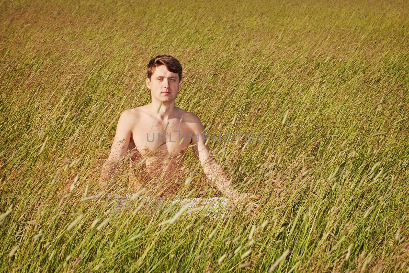 Man sits in grass in lotus pose by pzaxe