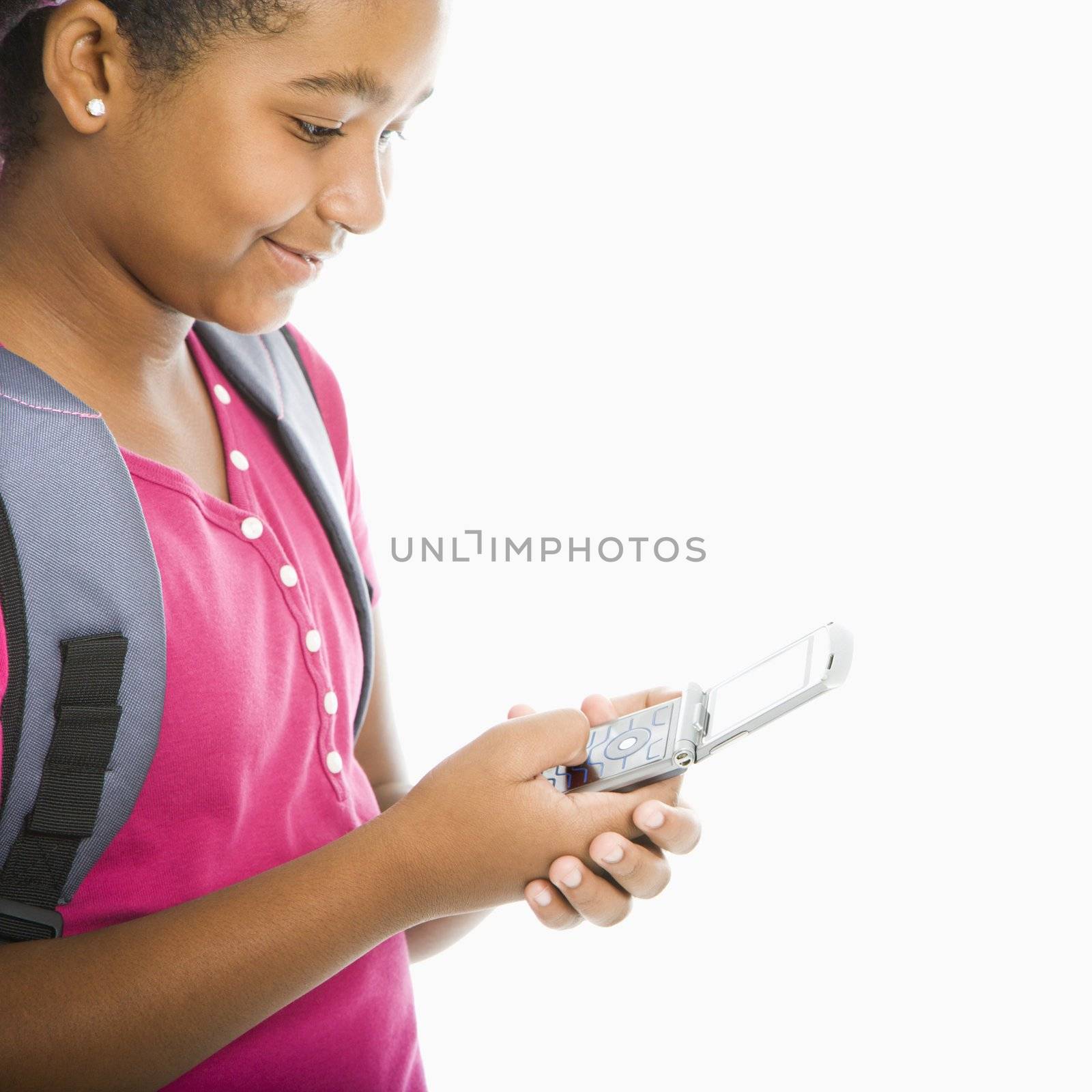 African American girl with backpack text messaging on cell phone.