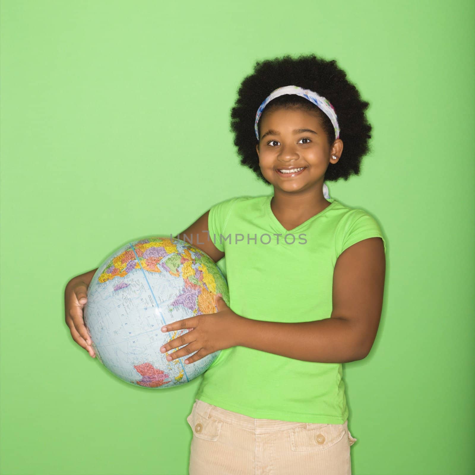 African American girl holding globe at hip and smiling at viewer.