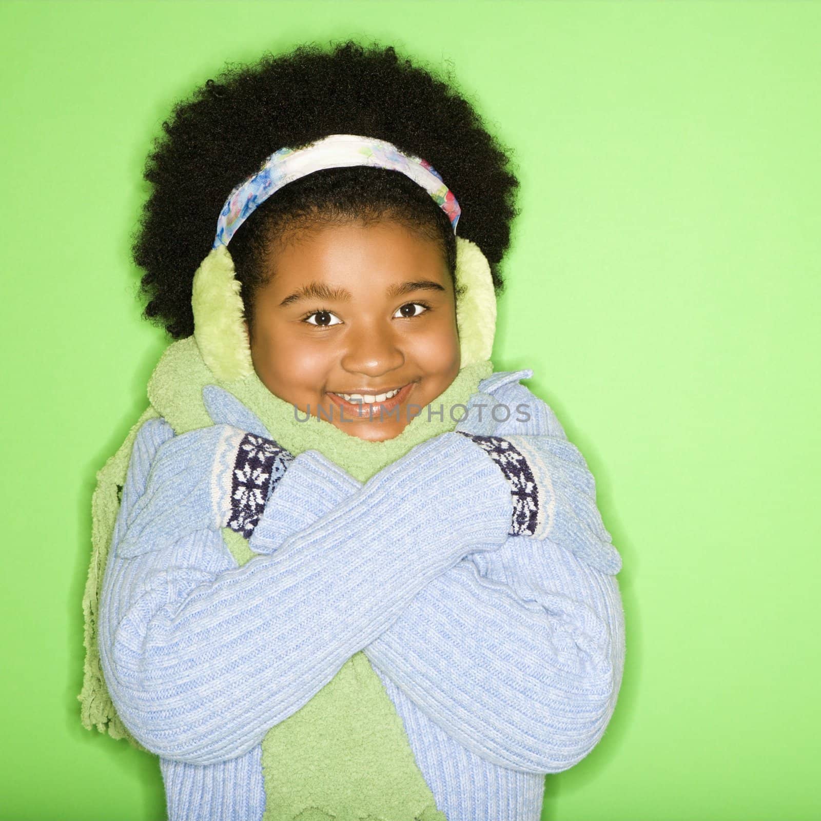 African American girl in winter clothing with arms crossed smiling at viewer.