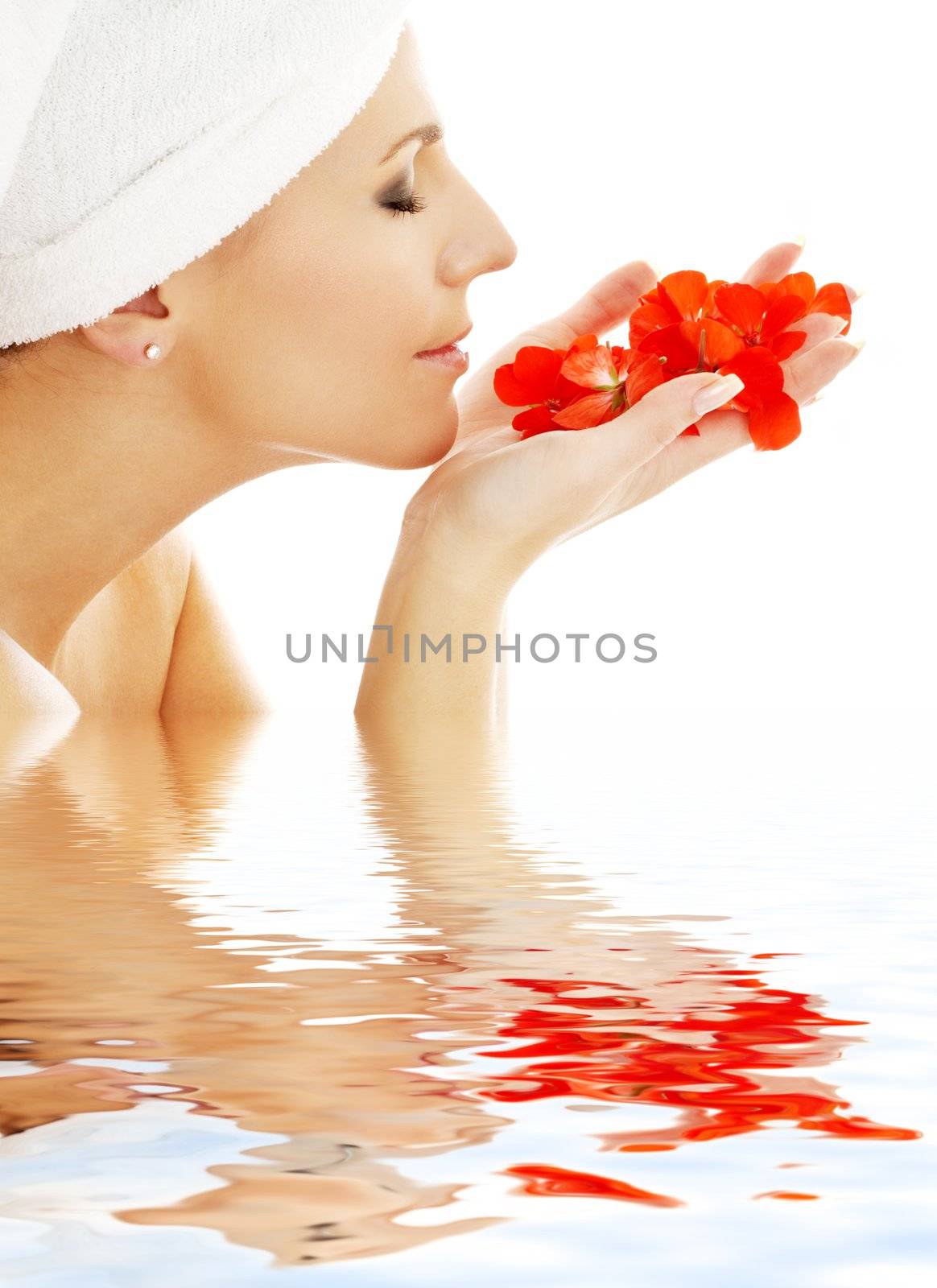 lovely woman smelling red flower petals in water