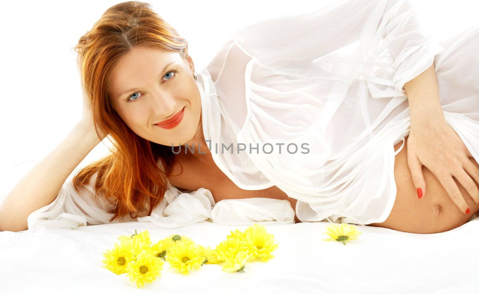 beautiful pregnant woman with yellow flowers in bed