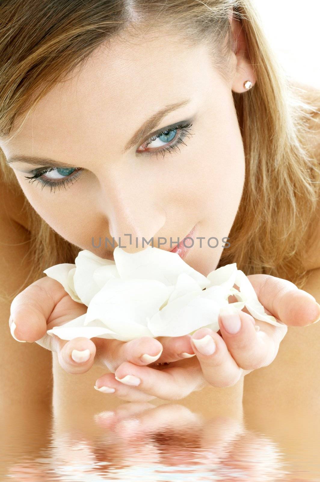 lovely woman smelling white rose petals in water