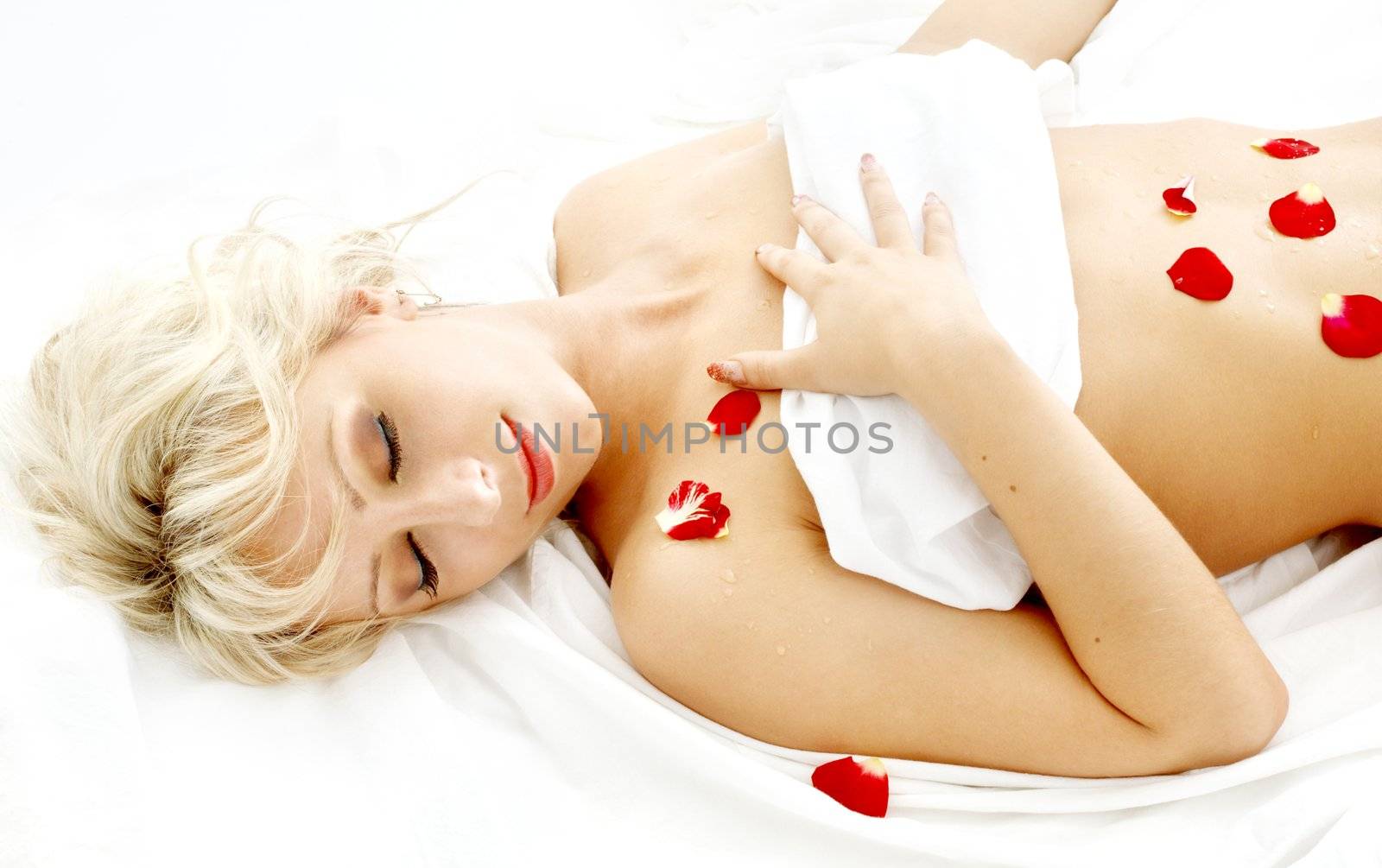 lovely blond with rose petals relaxing in spa