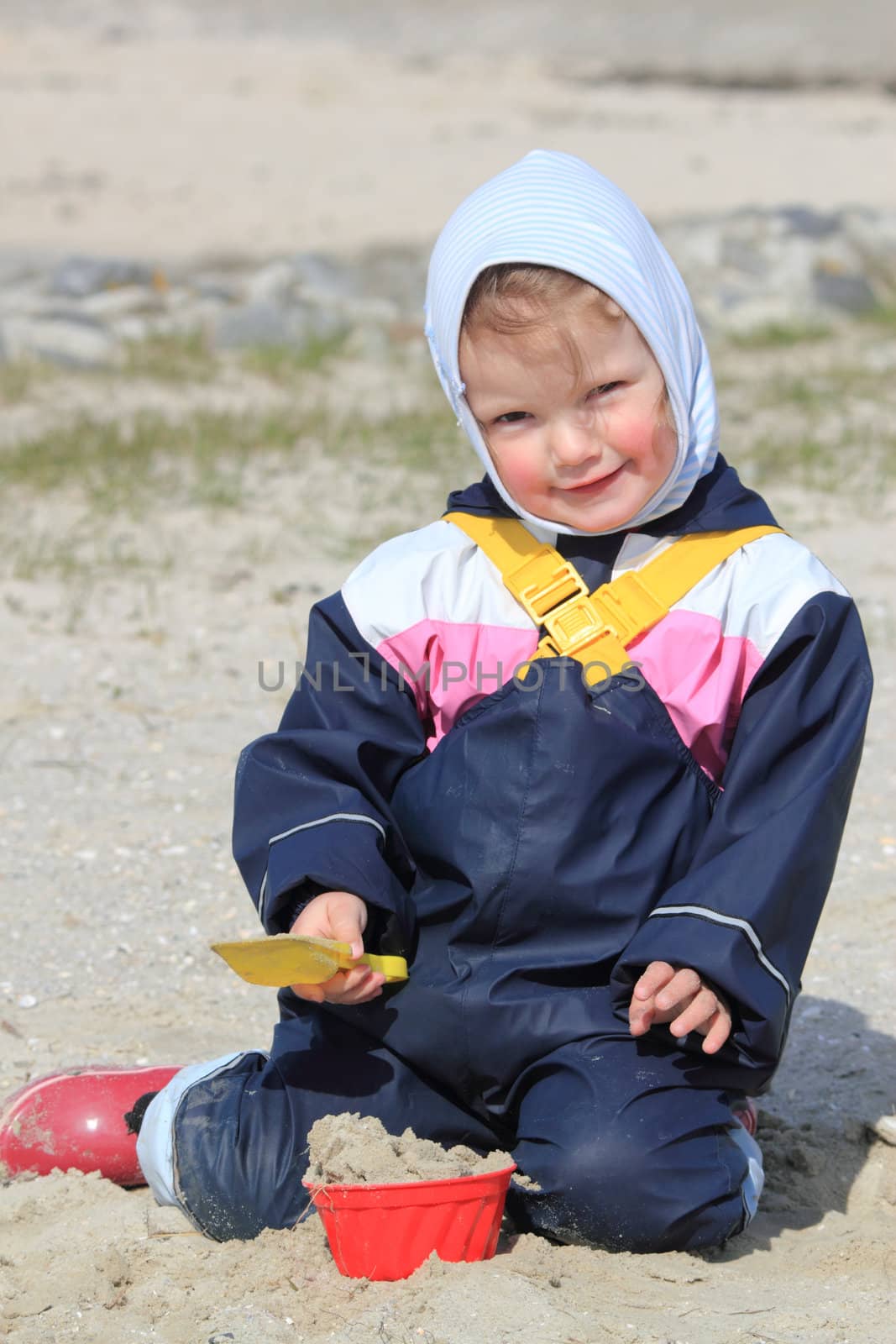 little girl with scoop playing at the beach