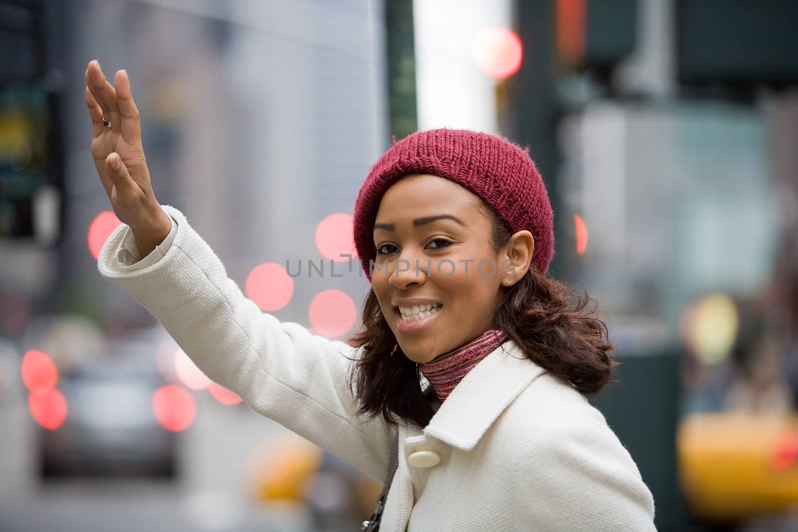 A pretty young business woman hails a taxi cab in the city.