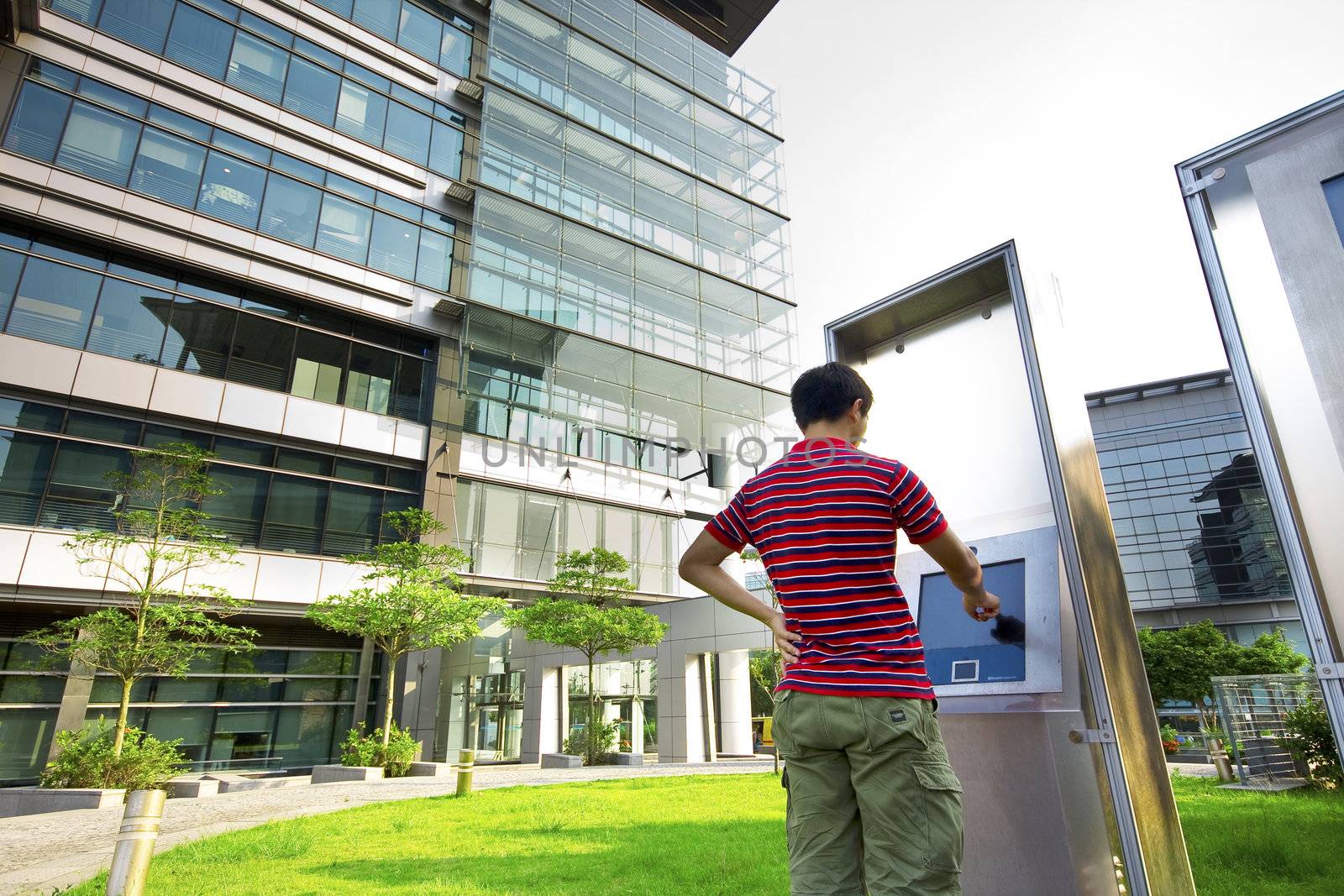 asia boy play the touch screen in modern building outside