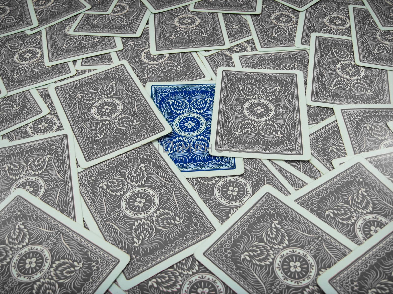 Blue coloured playing card surrounded by grey coloured playing cards