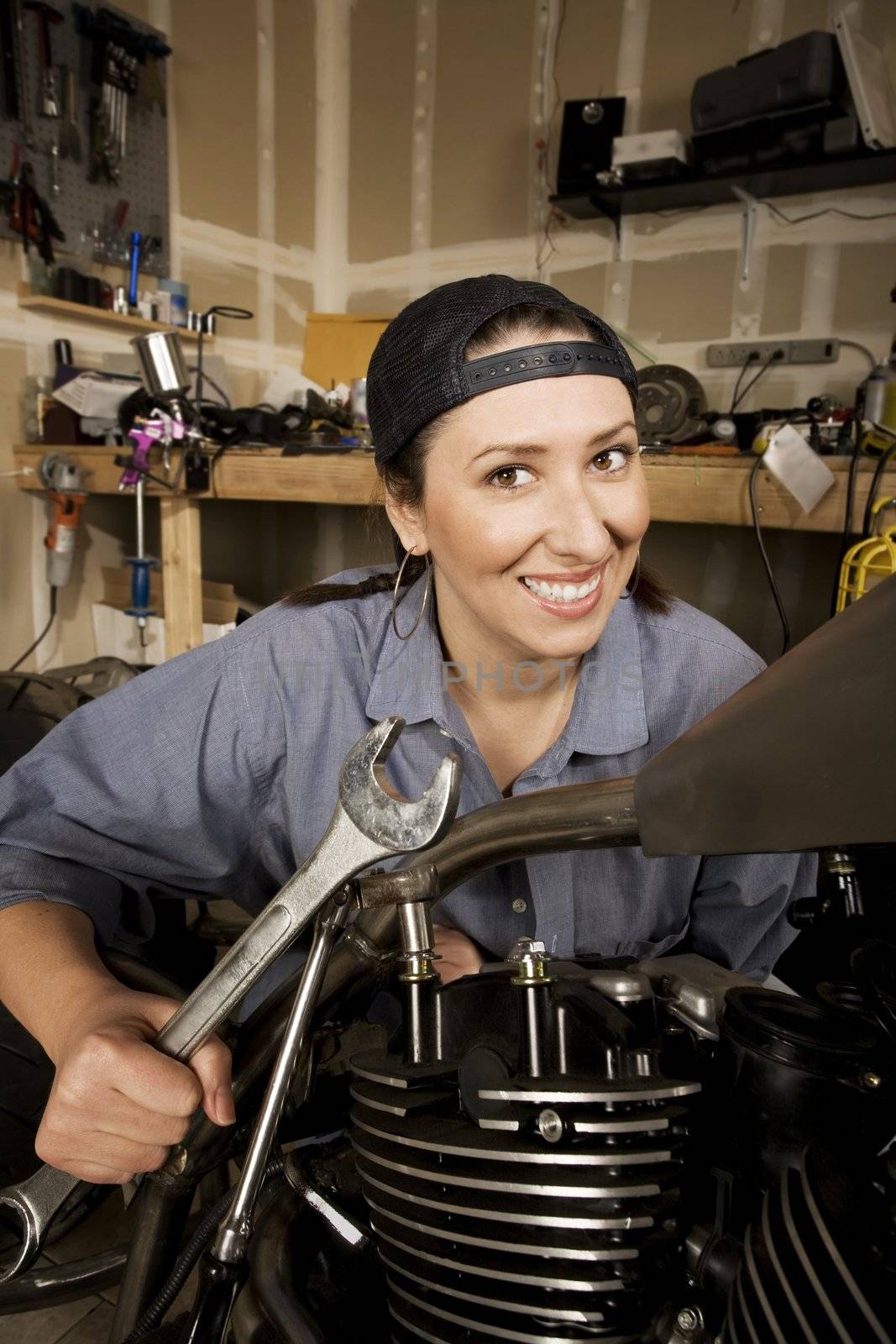 Female Hispanic mechanic working on a chopper style motorcycle