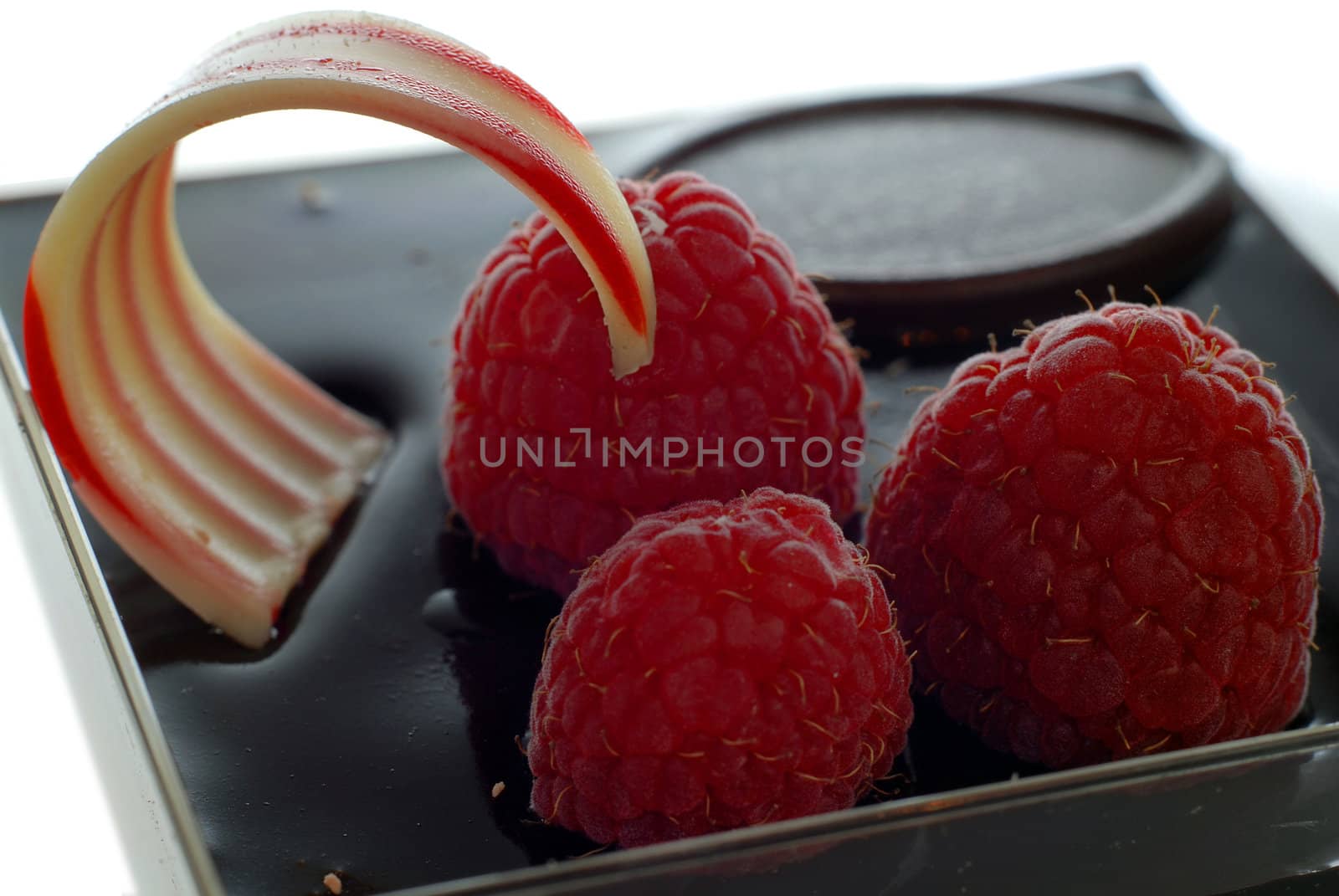 Close up of chocolate cake with raspberry and blueberry topping isolated on white background