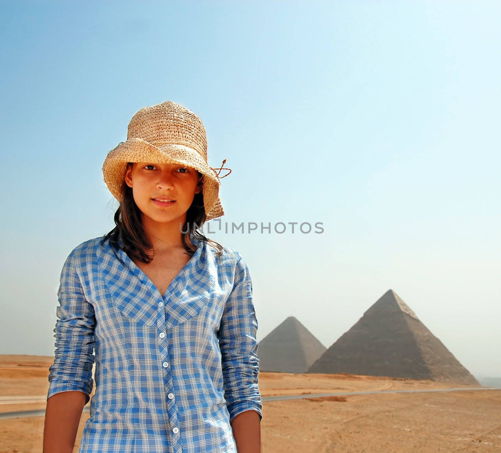 teenage girl tourist  in straw hat over pyramids in Egypt