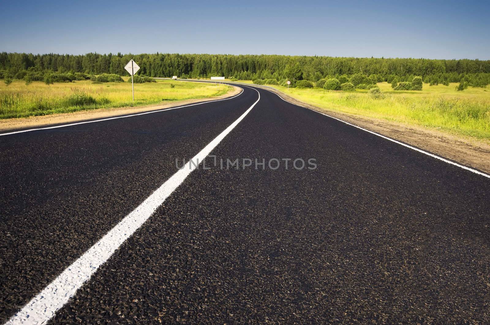 Road in a rural area with trees and blue sky