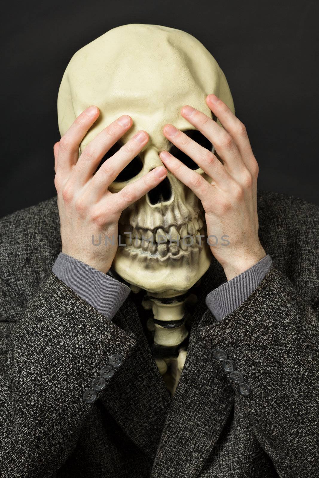 Skeleton covering his eyes on a dark background