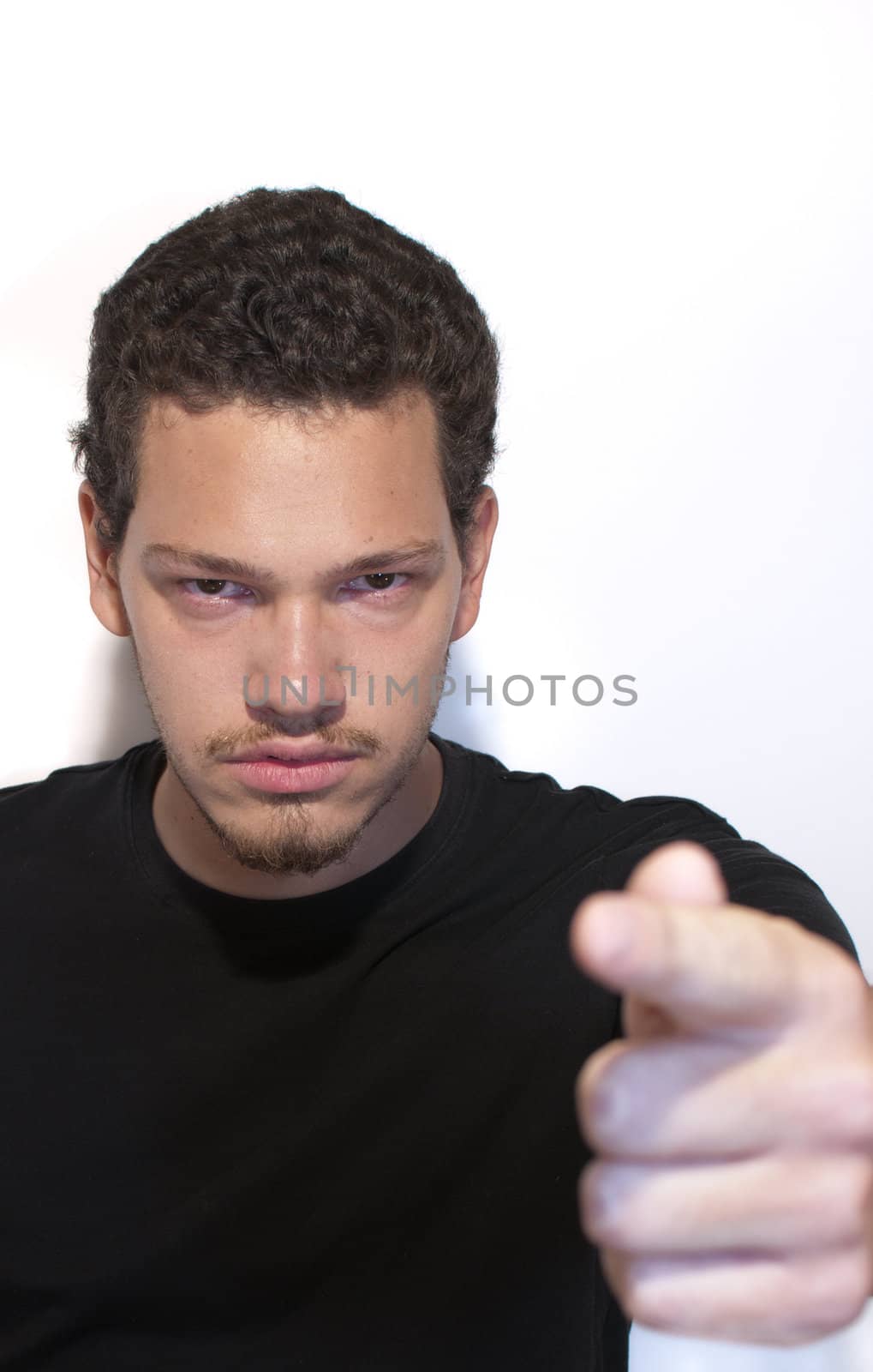 Serious young casual man pointing his finger on isolated background. (focus on man) 