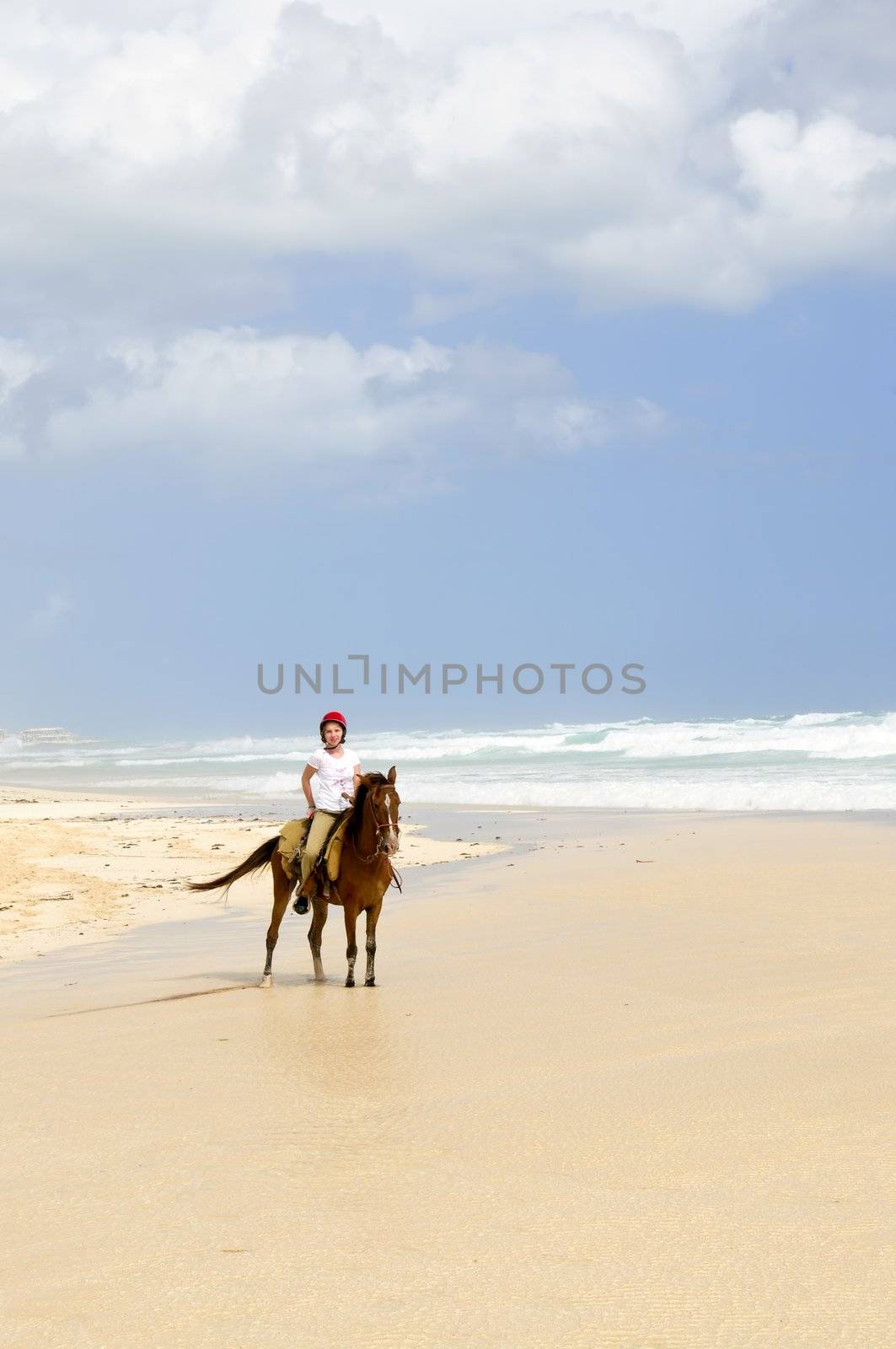 Young girl horseback riding on Caribbean beach