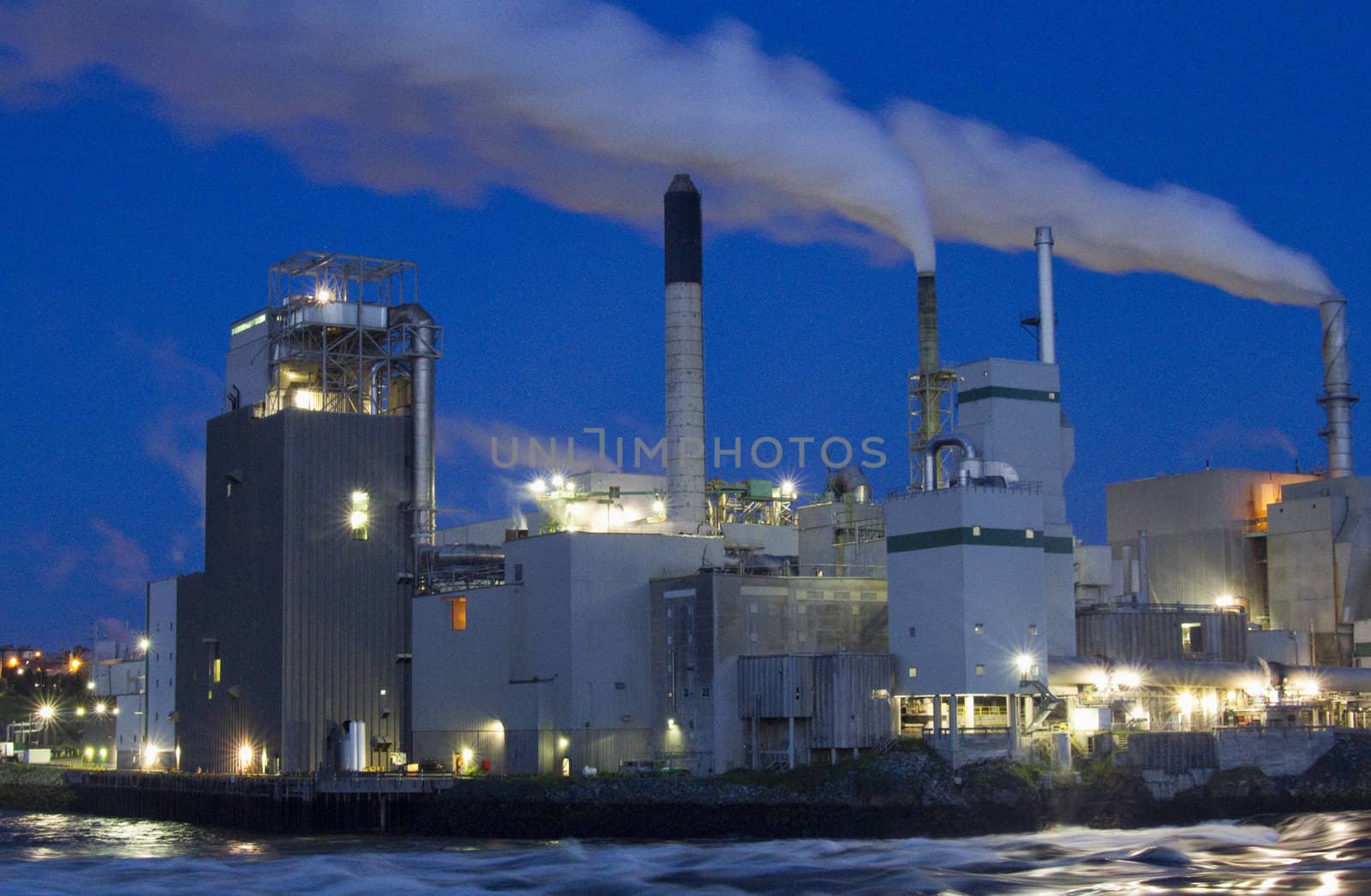 Clouds of steam emitting from smoke stakes at manufacturing facility in predawn light