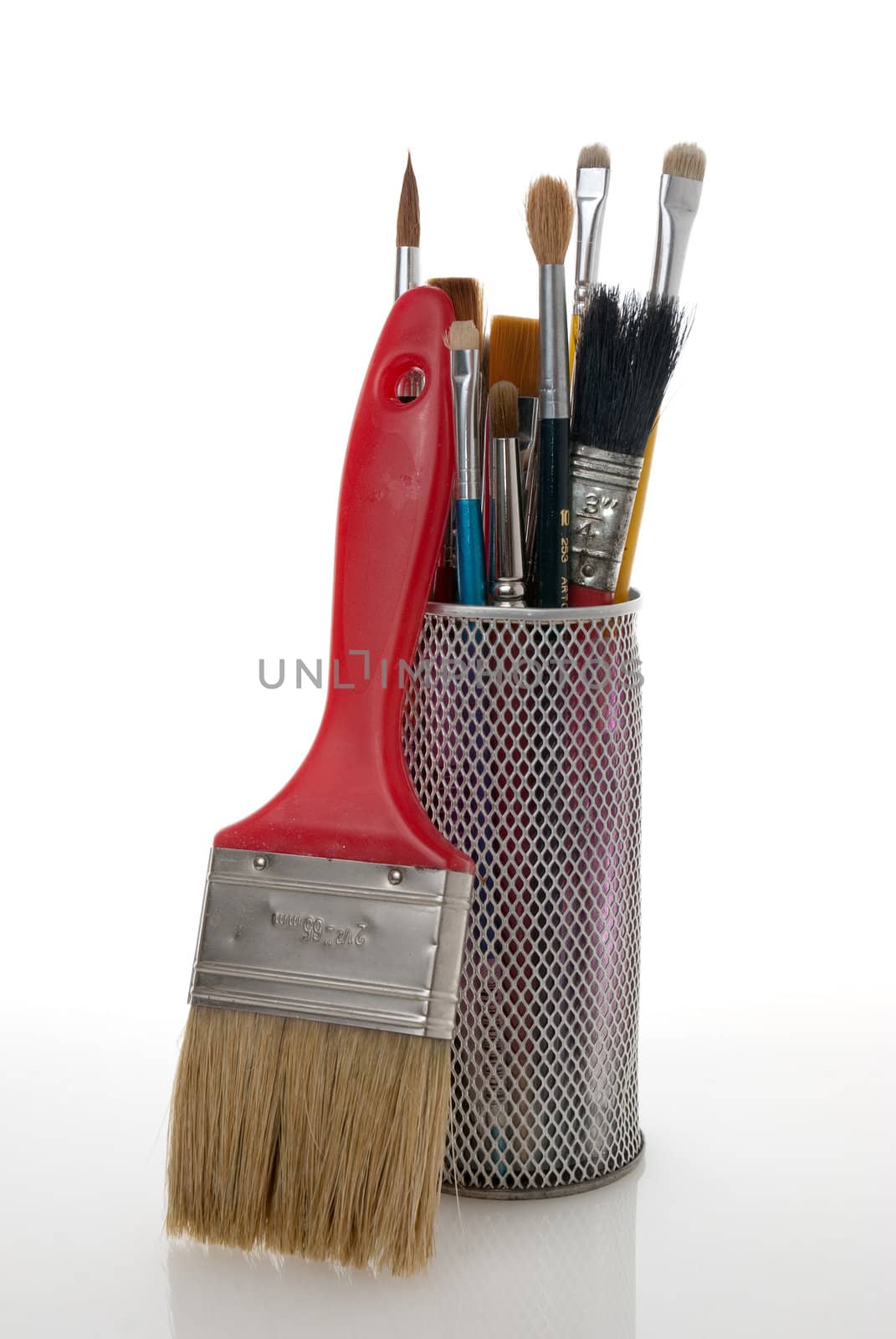 Paintbrushes in a metal mesh holder on white background.