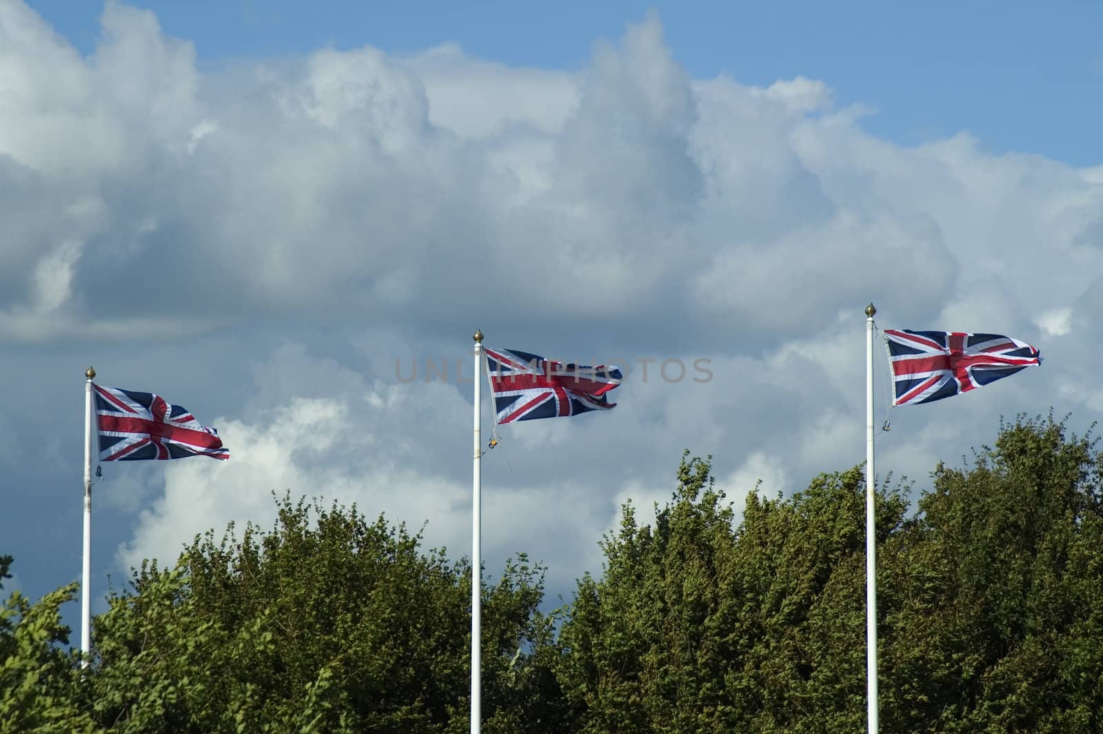 Three Union Flags of UK Flying on Flagpoles