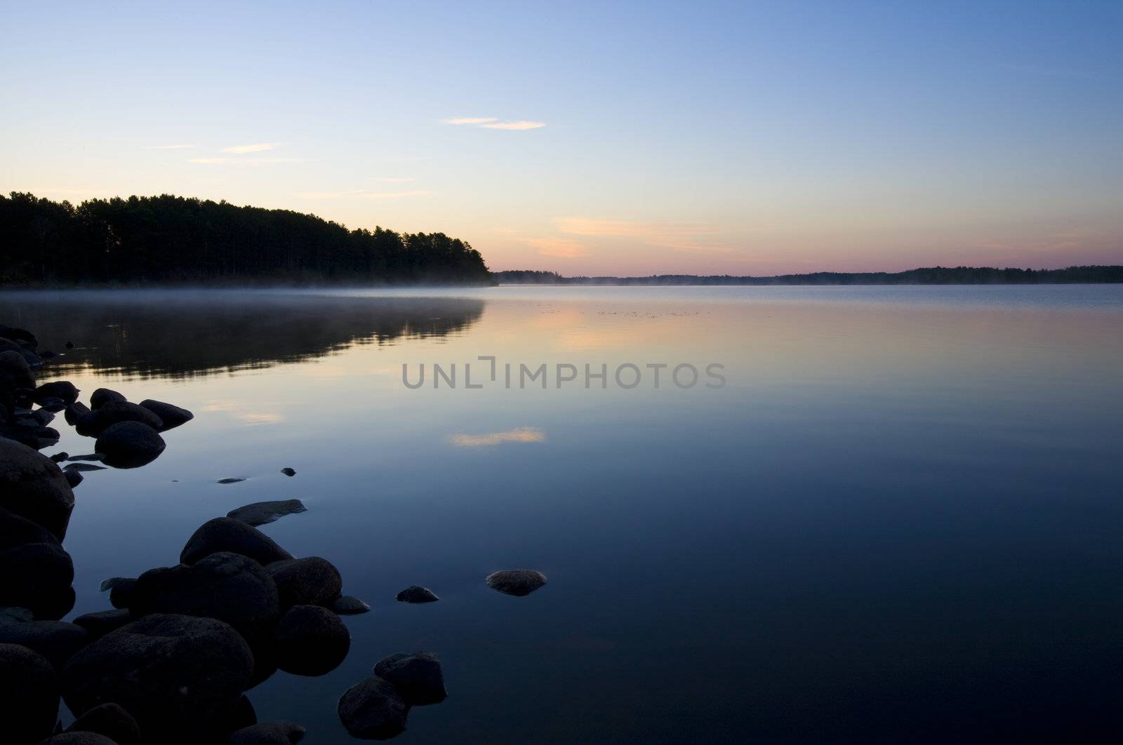 A blue misty lake at dawn in the North Woods of Minnesota