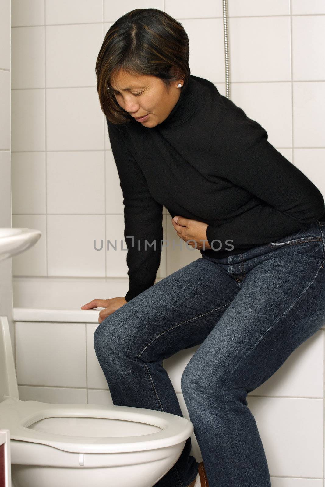 Asian woman with stomach sickness about to vomit into her toilet.
