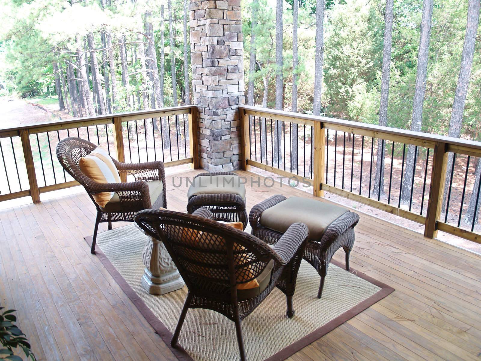 Wicker furniture sitting on a wooden deck overlooking a pine tree forest