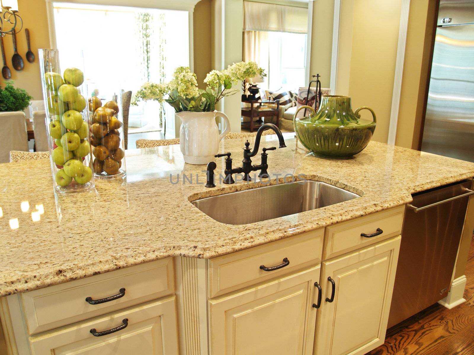 A granite topped island counter in a modern kitchen with dark hardware